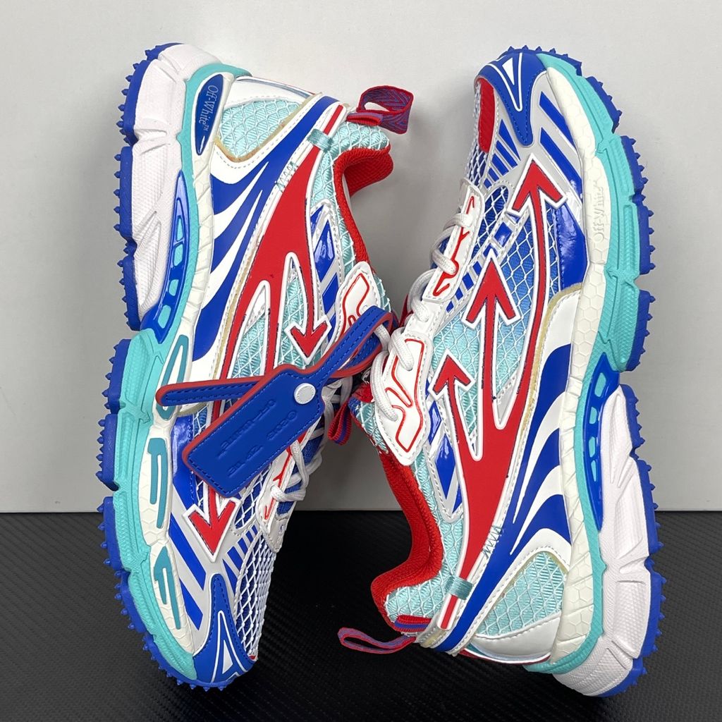 Side profile of the Off-White c/o Virgil Abloh sneaker showcasing a light blue mesh base, bold blue and red synthetic overlays, a large red arrow logo on the lateral side, and an attached blue and red zip-tie.