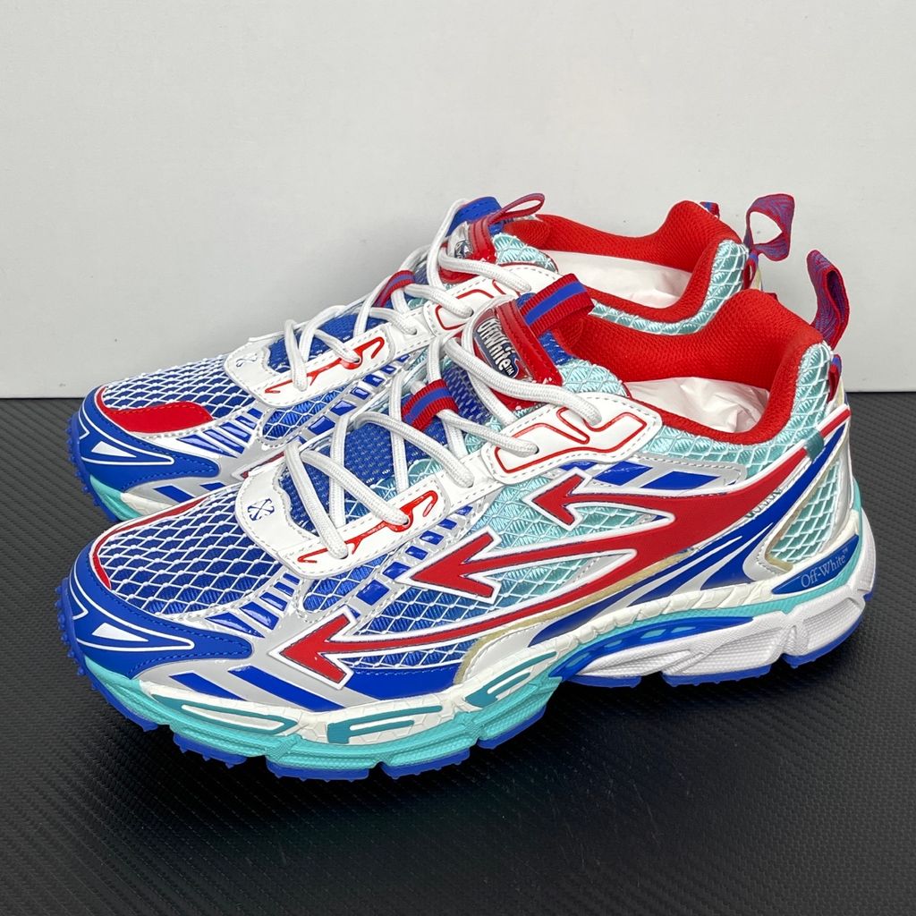 Side profile of the Off-White c/o Virgil Abloh sneaker showcasing a light blue mesh base, bold blue and red synthetic overlays, a large red arrow logo on the lateral side, and an attached blue and red zip-tie.