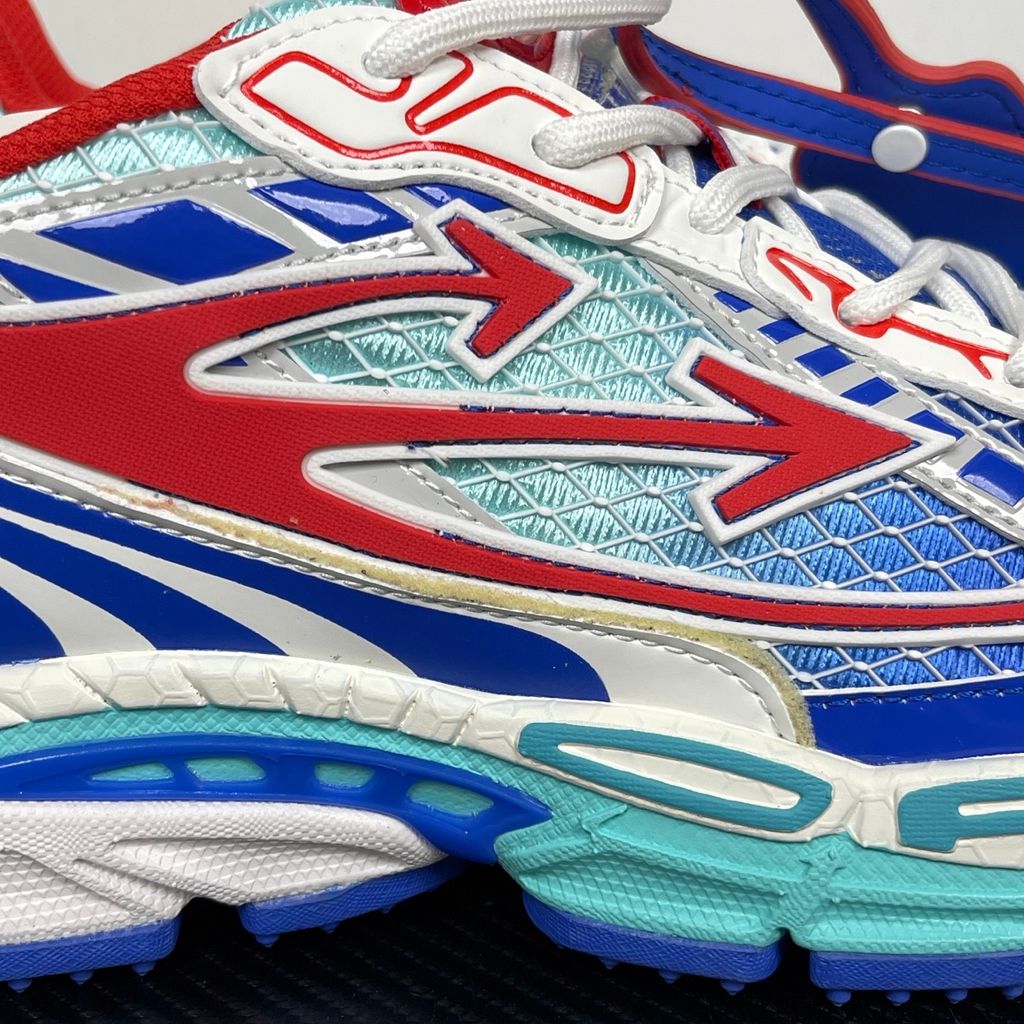 Side profile of the Off-White c/o Virgil Abloh sneaker showcasing a light blue mesh base, bold blue and red synthetic overlays, a large red arrow logo on the lateral side, and an attached blue and red zip-tie.