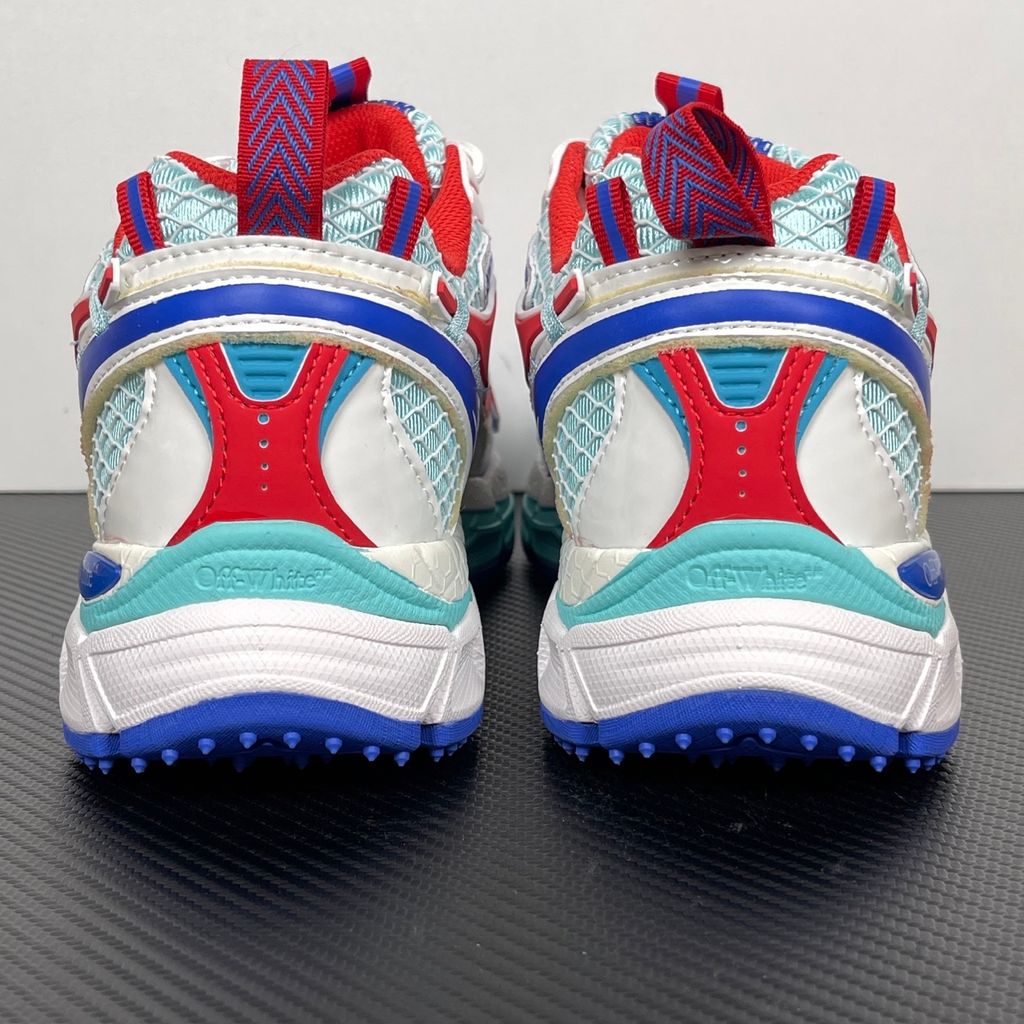 Side profile of the Off-White c/o Virgil Abloh sneaker showcasing a light blue mesh base, bold blue and red synthetic overlays, a large red arrow logo on the lateral side, and an attached blue and red zip-tie.