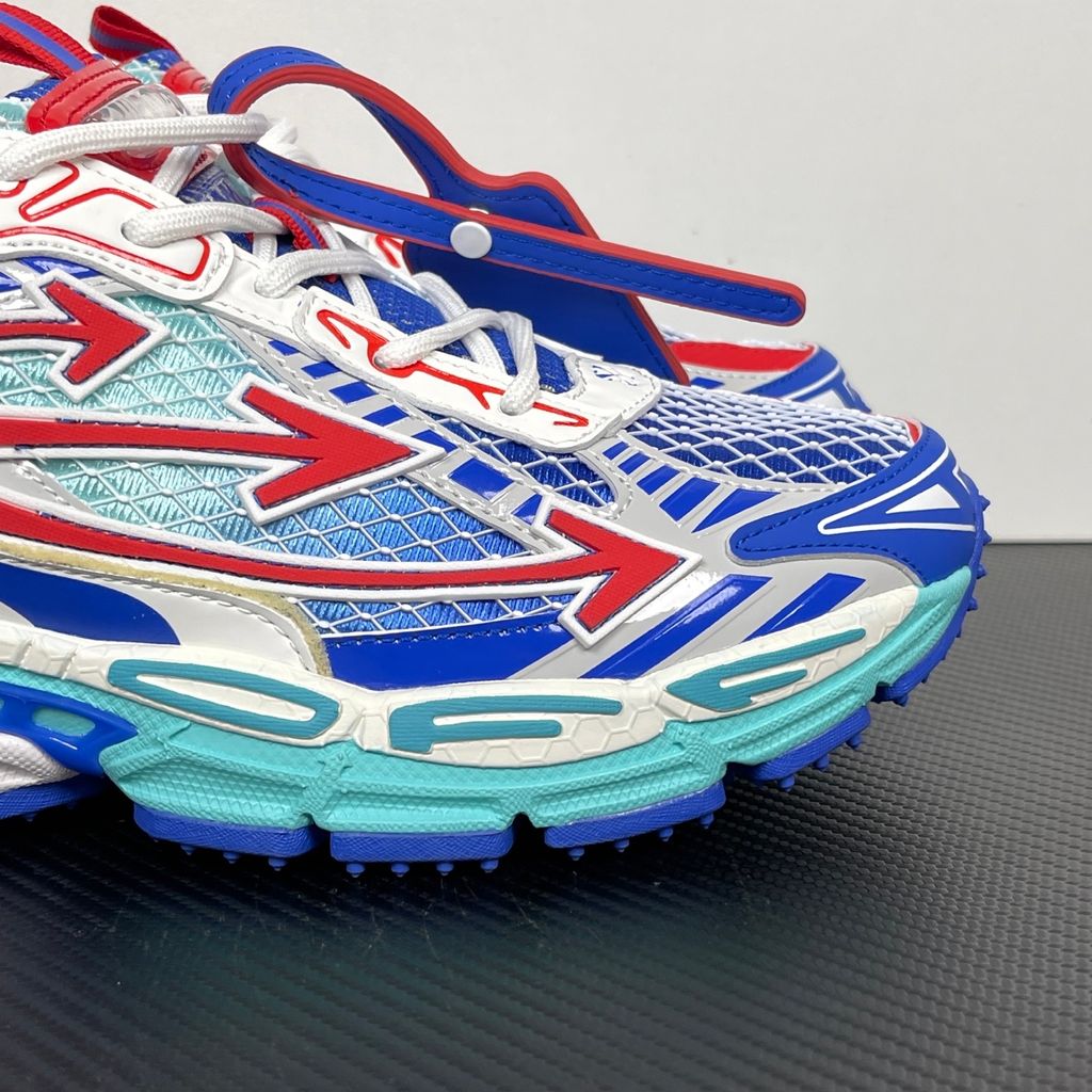 Side profile of the Off-White c/o Virgil Abloh sneaker showcasing a light blue mesh base, bold blue and red synthetic overlays, a large red arrow logo on the lateral side, and an attached blue and red zip-tie.