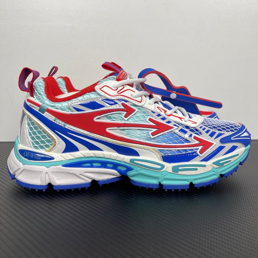 Side profile of the Off-White c/o Virgil Abloh sneaker showcasing a light blue mesh base, bold blue and red synthetic overlays, a large red arrow logo on the lateral side, and an attached blue and red zip-tie.