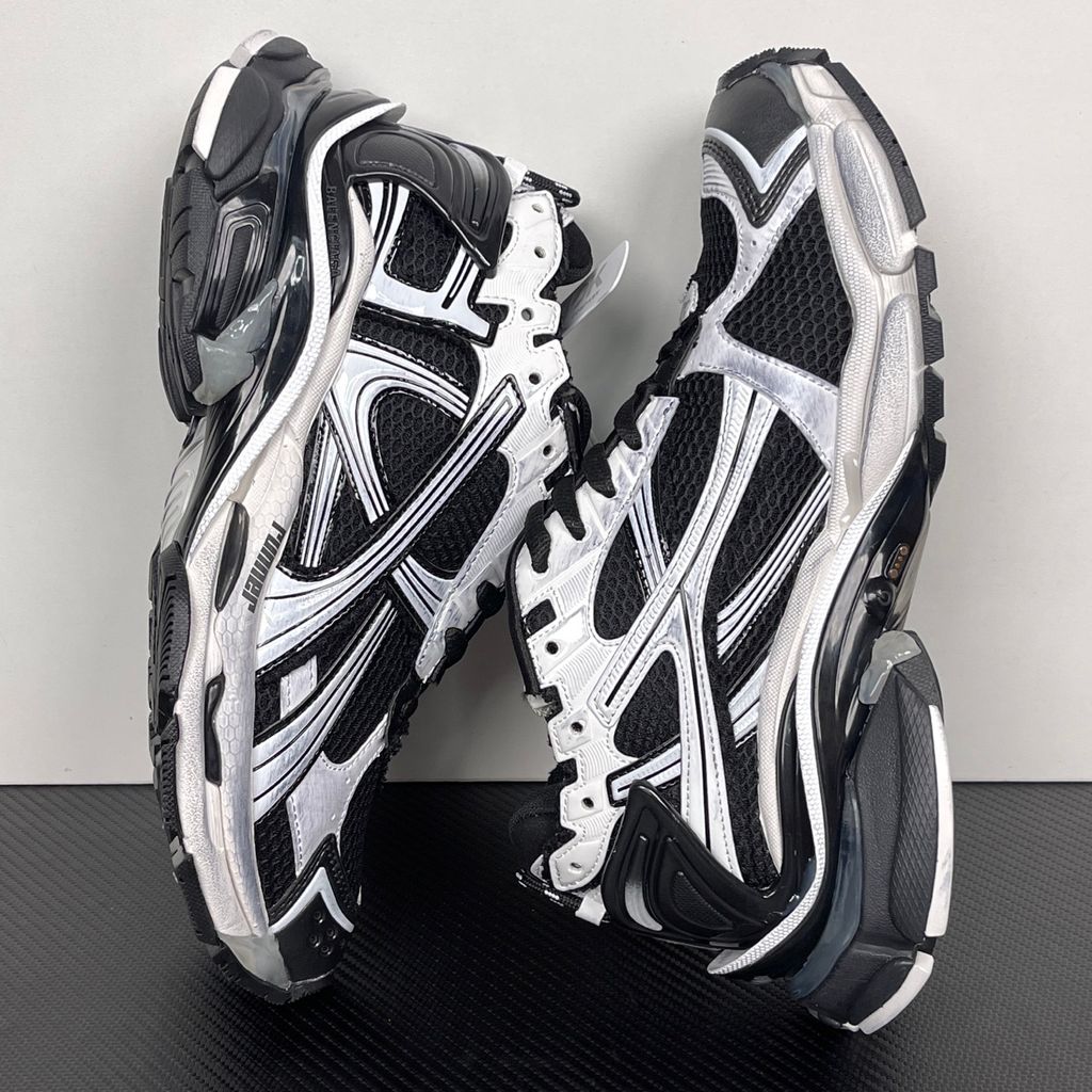 Side profile of the Balenciaga Runner LED sneaker in the 'Black/White' colorway, highlighting the intricate multi-layered mesh and synthetic construction, high-contrast paneling, and the clear heel capsule housing the LED technology.