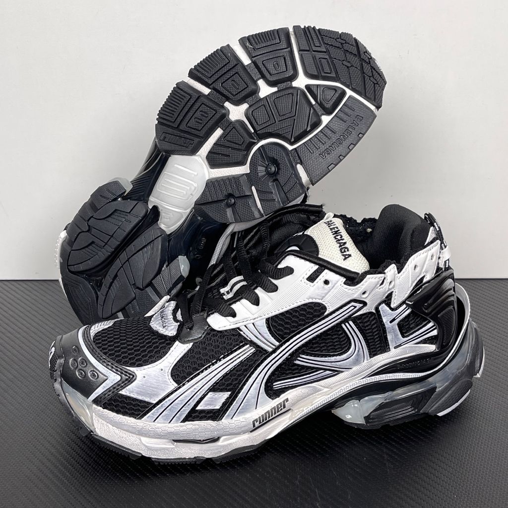 Side profile of the Balenciaga Runner LED sneaker in the 'Black/White' colorway, highlighting the intricate multi-layered mesh and synthetic construction, high-contrast paneling, and the clear heel capsule housing the LED technology.
