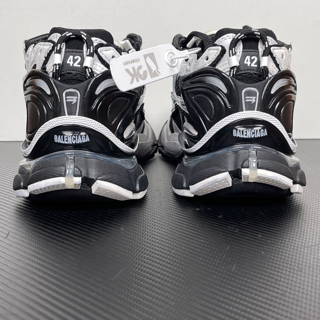 Side profile of the Balenciaga Runner LED sneaker in the 'Black/White' colorway, highlighting the intricate multi-layered mesh and synthetic construction, high-contrast paneling, and the clear heel capsule housing the LED technology.