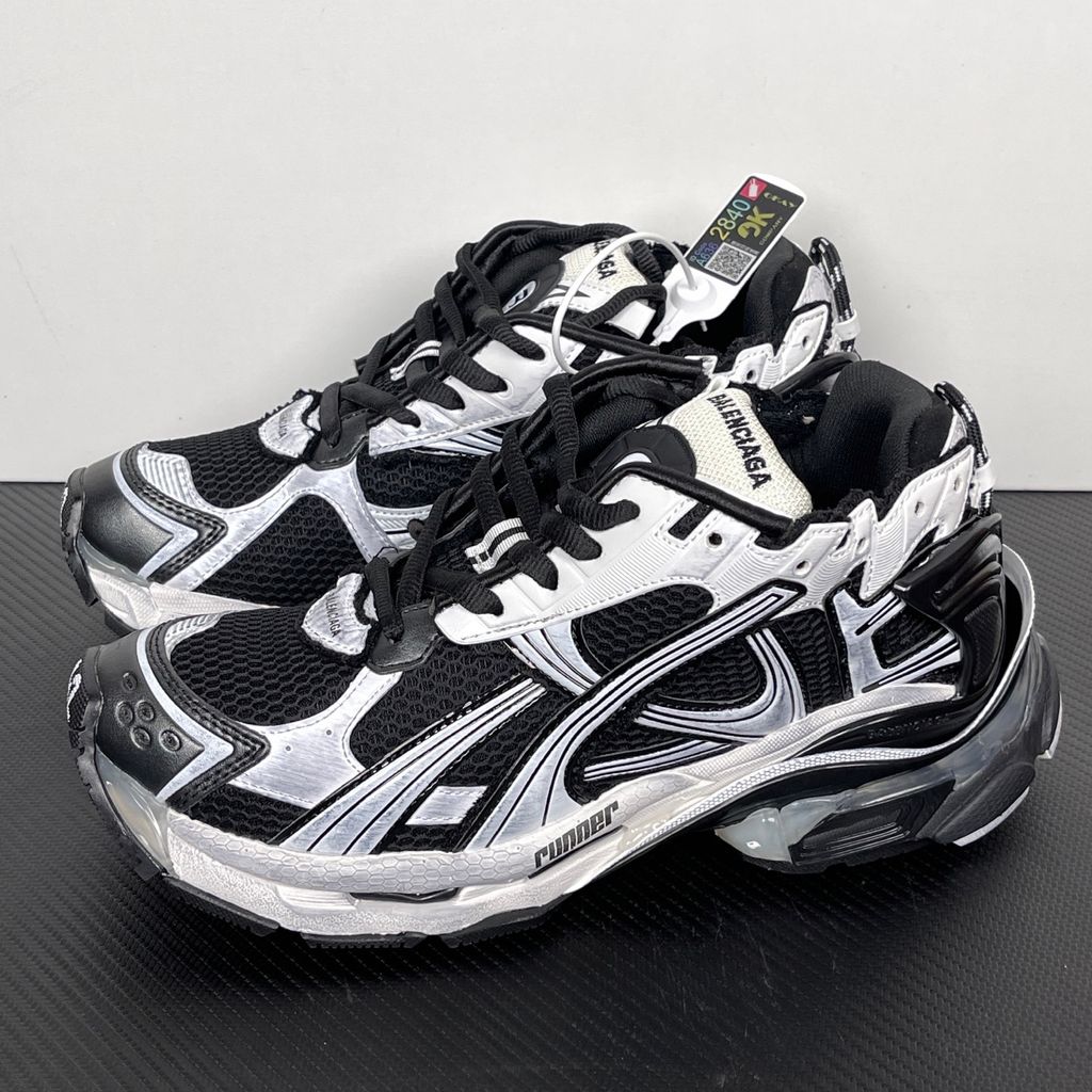 Side profile of the Balenciaga Runner LED sneaker in the 'Black/White' colorway, highlighting the intricate multi-layered mesh and synthetic construction, high-contrast paneling, and the clear heel capsule housing the LED technology.