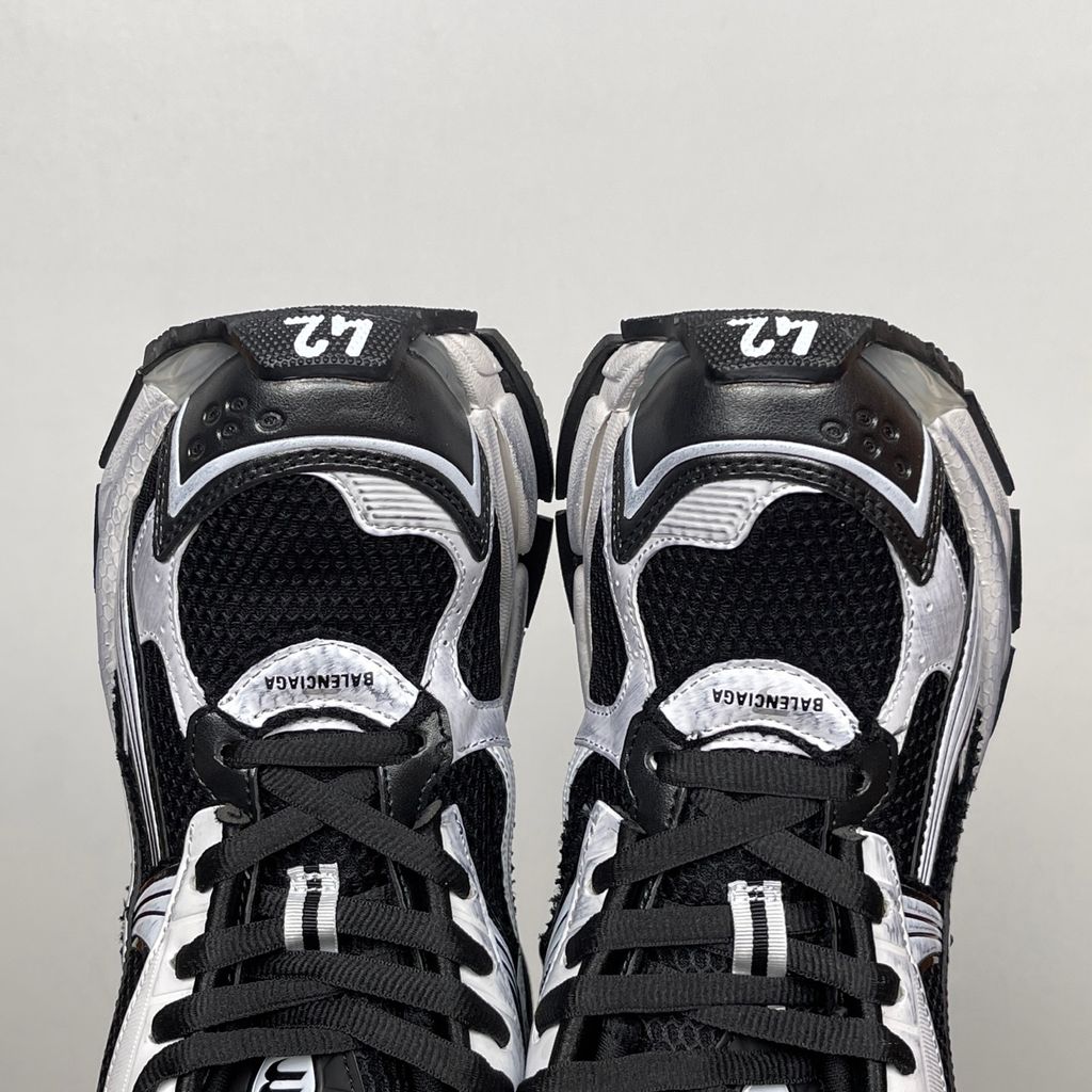 Side profile of the Balenciaga Runner LED sneaker in the 'Black/White' colorway, highlighting the intricate multi-layered mesh and synthetic construction, high-contrast paneling, and the clear heel capsule housing the LED technology.
