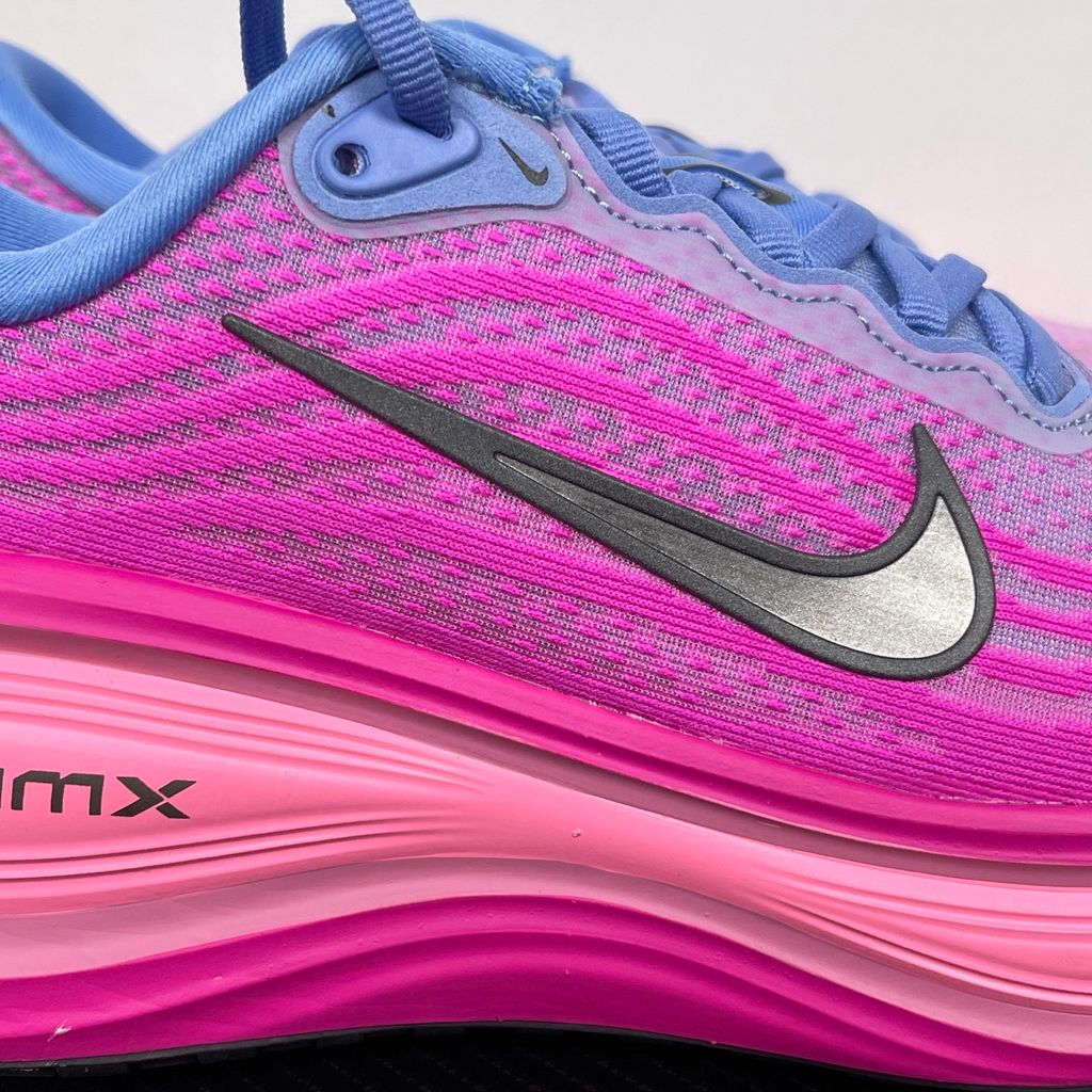 Side profile of the Nike Women's Vomero Plus running shoe, featuring a vibrant pink and purple engineered mesh upper, a metallic dark grey Swoosh, and a heavily cushioned, sculpted pink ZoomX foam midsole.