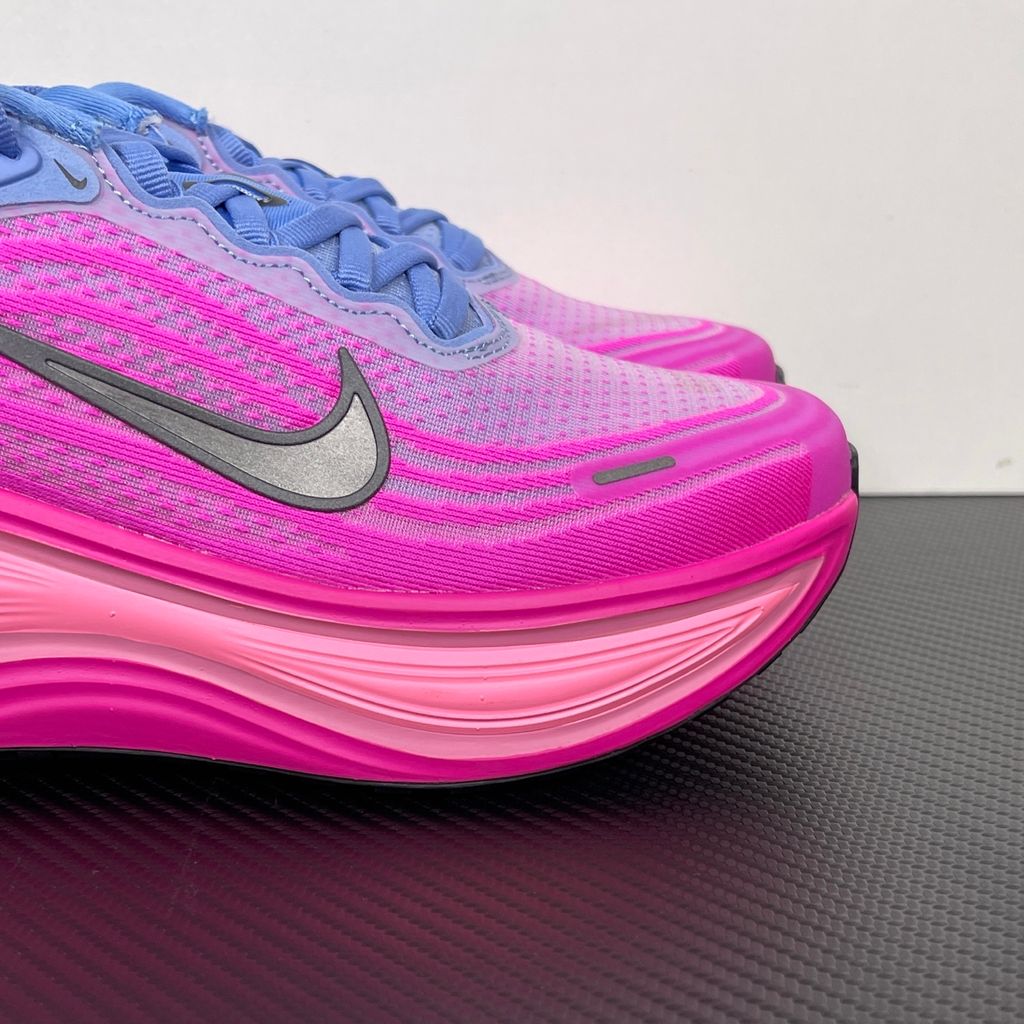 Side profile of the Nike Women's Vomero Plus running shoe, featuring a vibrant pink and purple engineered mesh upper, a metallic dark grey Swoosh, and a heavily cushioned, sculpted pink ZoomX foam midsole.