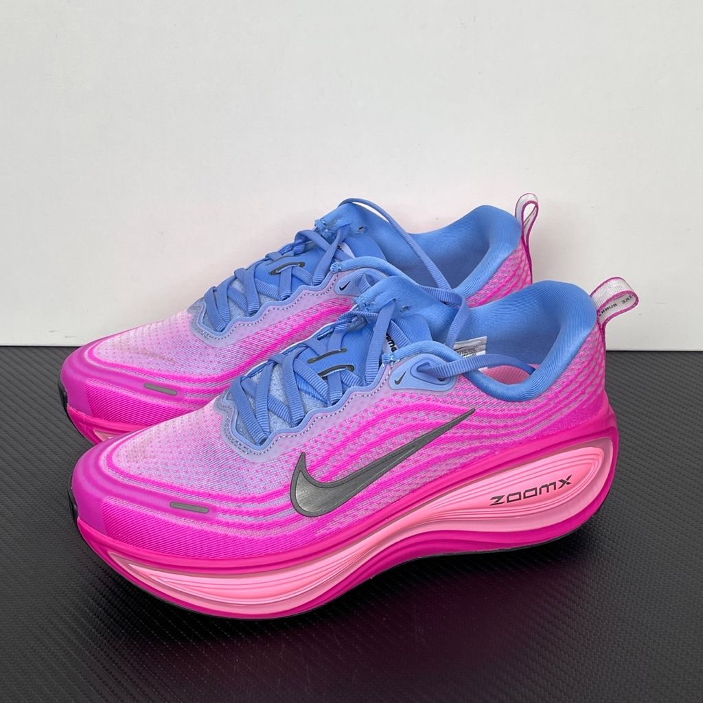 Side profile of the Nike Women's Vomero Plus running shoe, featuring a vibrant pink and purple engineered mesh upper, a metallic dark grey Swoosh, and a heavily cushioned, sculpted pink ZoomX foam midsole.