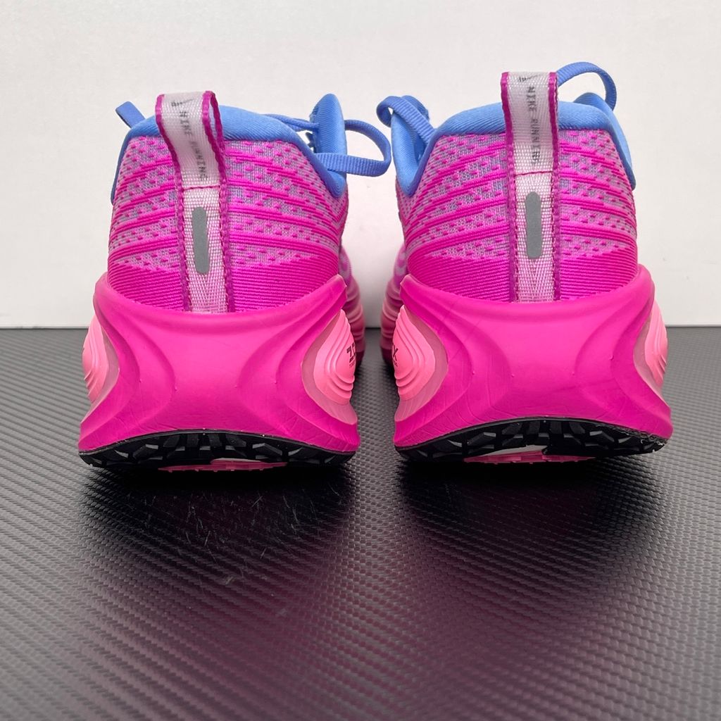 Side profile of the Nike Women's Vomero Plus running shoe, featuring a vibrant pink and purple engineered mesh upper, a metallic dark grey Swoosh, and a heavily cushioned, sculpted pink ZoomX foam midsole.