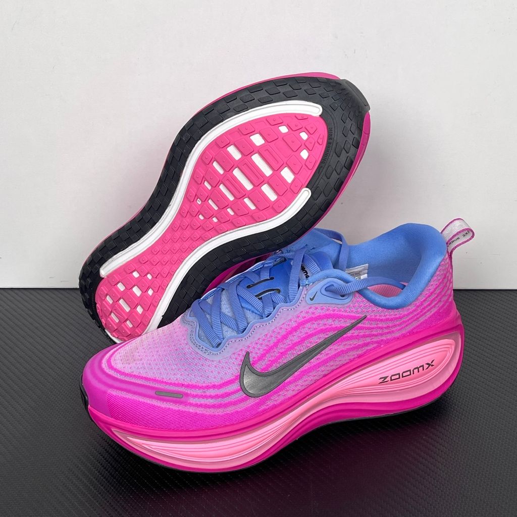 Side profile of the Nike Women's Vomero Plus running shoe, featuring a vibrant pink and purple engineered mesh upper, a metallic dark grey Swoosh, and a heavily cushioned, sculpted pink ZoomX foam midsole.
