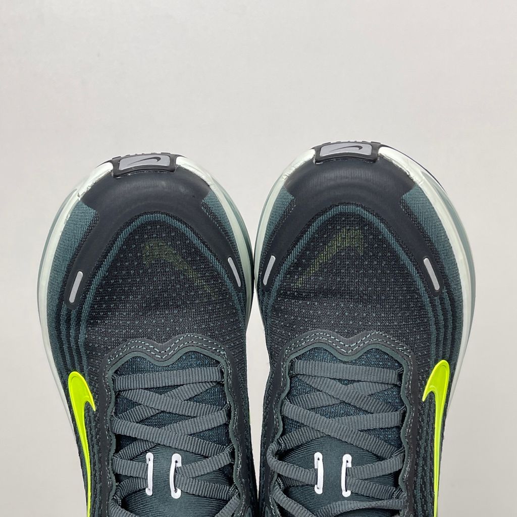 Side profile of the Nike Vomero Plus running shoe, featuring an earthy green engineered mesh upper with Seaweed and Cannon overlays, striking neon Volt accents, and a heavily cushioned, sculpted ZoomX foam midsole.