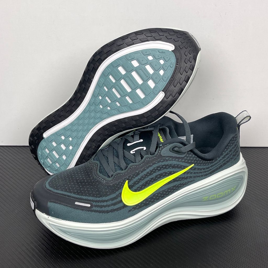 Side profile of the Nike Vomero Plus running shoe, featuring an earthy green engineered mesh upper with Seaweed and Cannon overlays, striking neon Volt accents, and a heavily cushioned, sculpted ZoomX foam midsole.