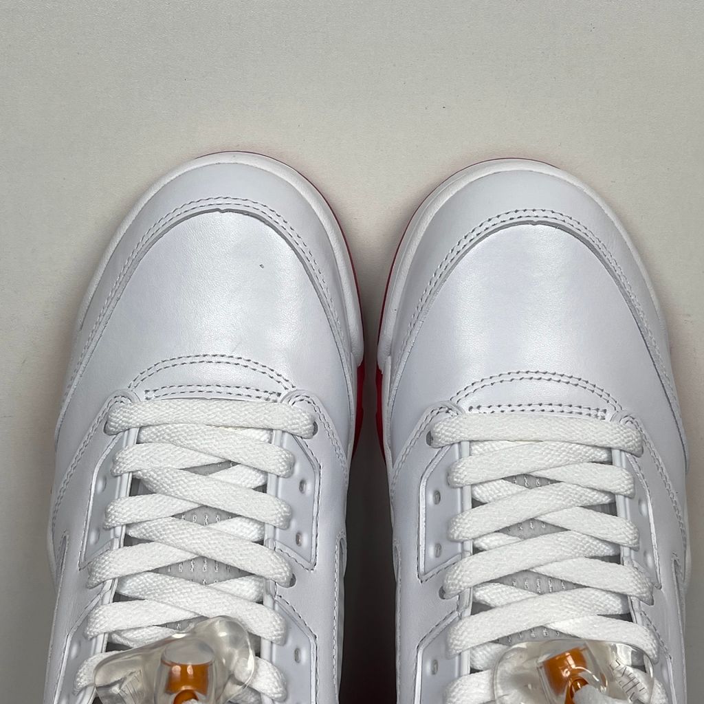Side profile of the Air Jordan 5 Retro sneaker in the 'Sunset' colorway, featuring a crisp leather upper, vibrant orange and red sunset gradient accents, signature translucent netting, and the iconic shark tooth midsole detailing.
