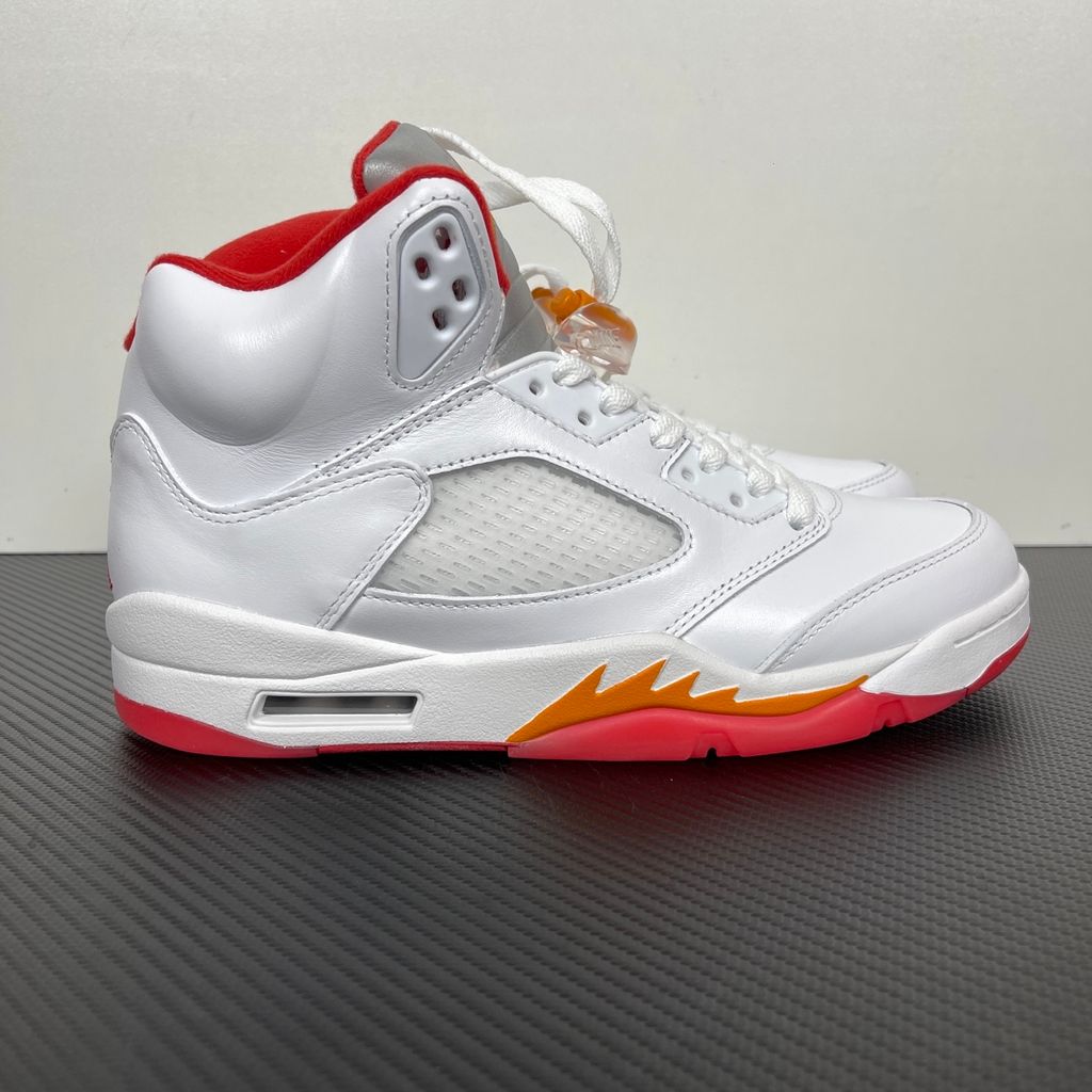 Side profile of the Air Jordan 5 Retro sneaker in the 'Sunset' colorway, featuring a crisp leather upper, vibrant orange and red sunset gradient accents, signature translucent netting, and the iconic shark tooth midsole detailing.