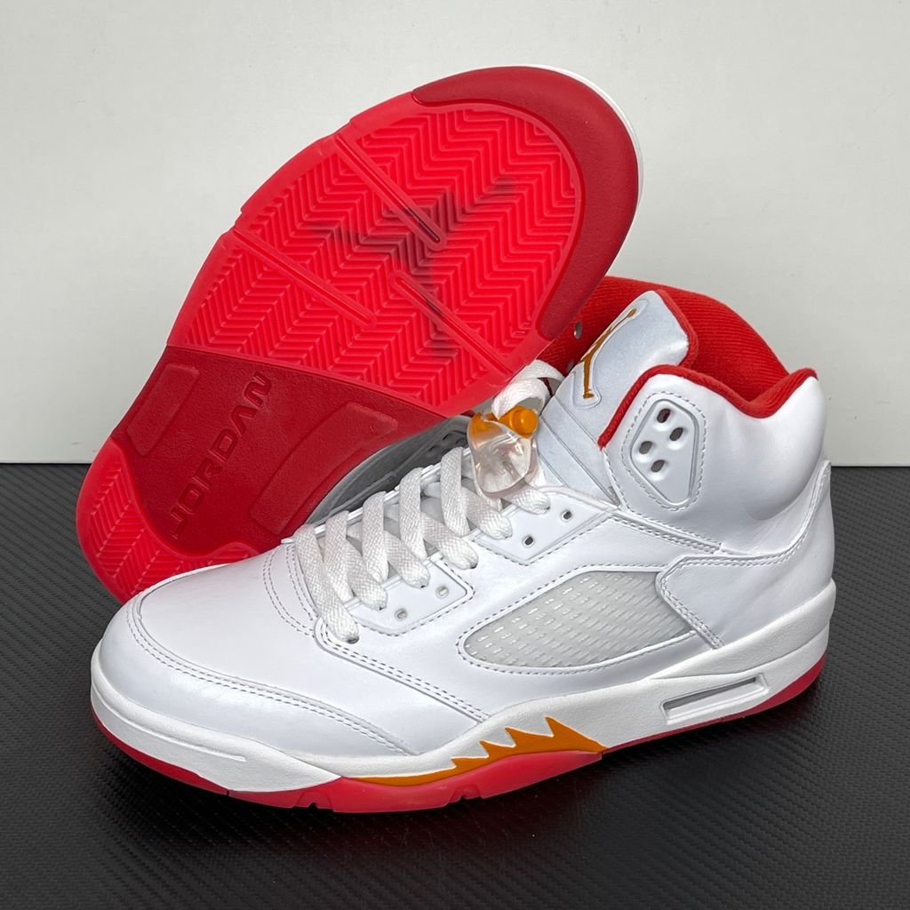 Side profile of the Air Jordan 5 Retro sneaker in the 'Sunset' colorway, featuring a crisp leather upper, vibrant orange and red sunset gradient accents, signature translucent netting, and the iconic shark tooth midsole detailing.