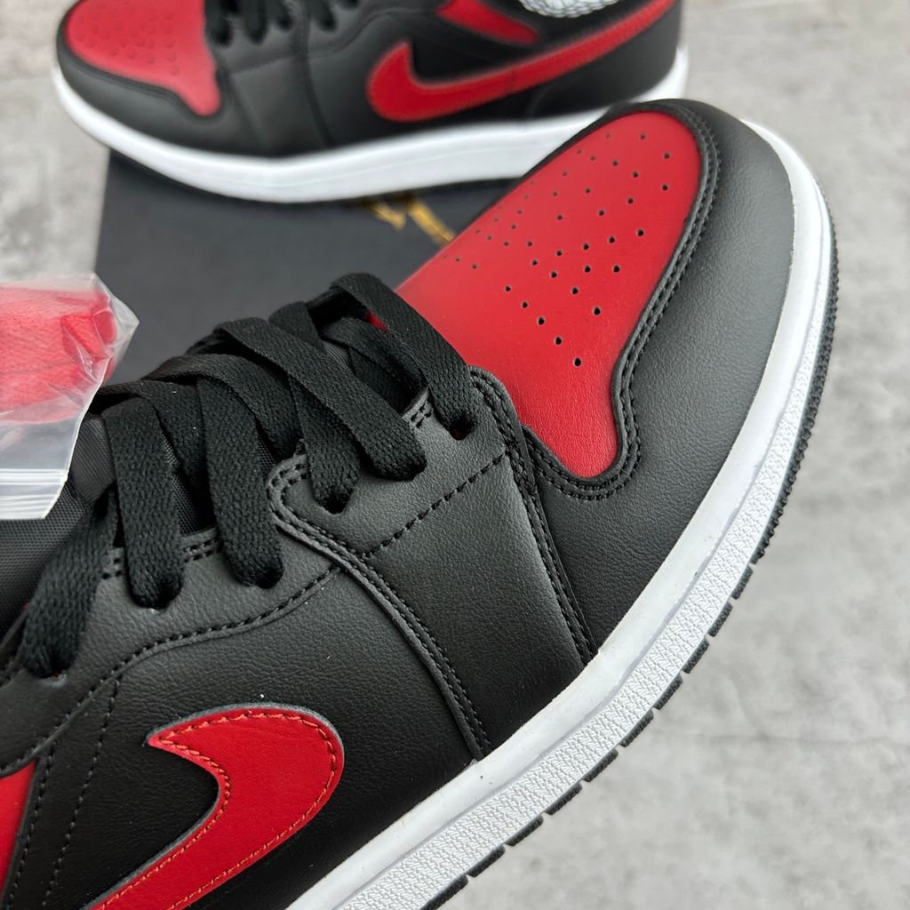 Side profile of the Air Jordan 1 Mid sneaker in the 'Bred Twist' colorway, featuring a crisp white leather base, bold black overlays, and vibrant University Red accents on the Swoosh, collar, and outsole.