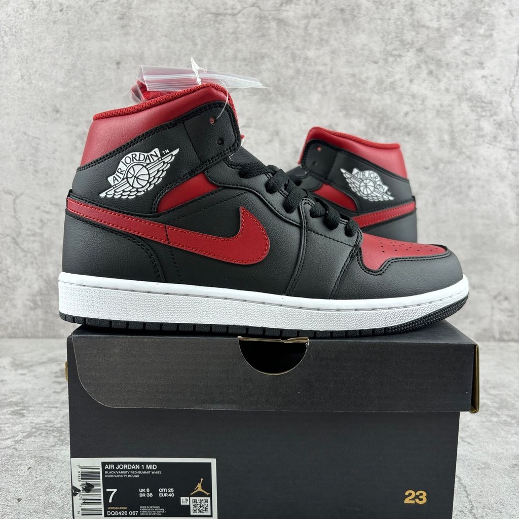 Side profile of the Air Jordan 1 Mid sneaker in the 'Bred Twist' colorway, featuring a crisp white leather base, bold black overlays, and vibrant University Red accents on the Swoosh, collar, and outsole.