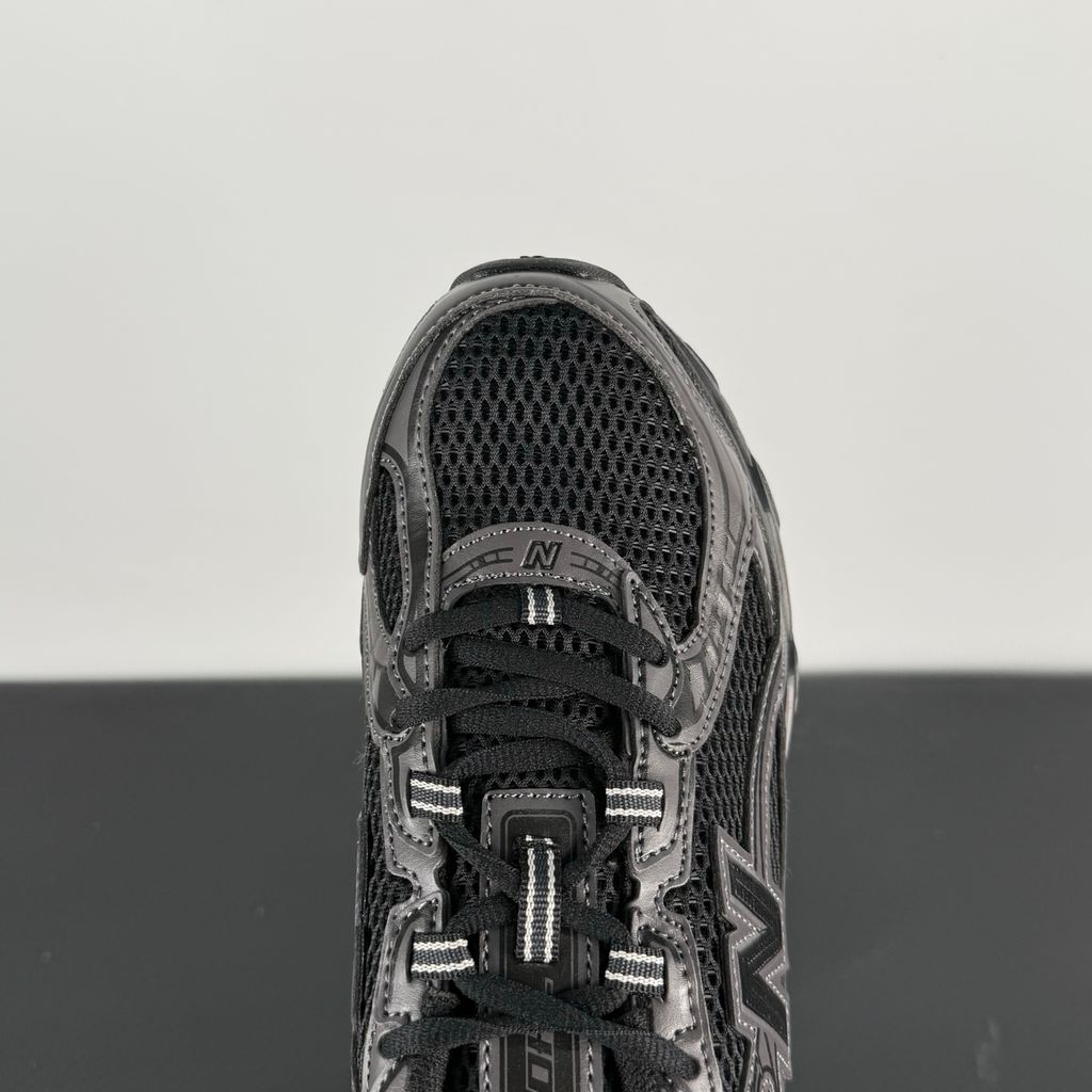 Side profile of the New Balance 740 sneaker in the 'Triple Black' colorway, showcasing the monochromatic mesh and synthetic upper, the tonal 'N' side logo, and the sculpted black midsole.