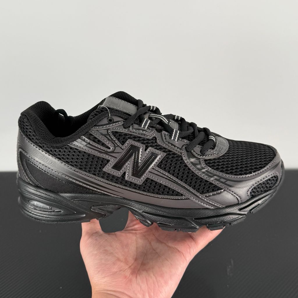Side profile of the New Balance 740 sneaker in the 'Triple Black' colorway, showcasing the monochromatic mesh and synthetic upper, the tonal 'N' side logo, and the sculpted black midsole.