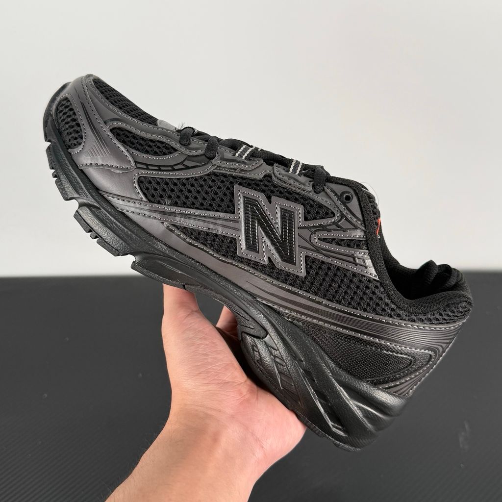 Side profile of the New Balance 740 sneaker in the 'Triple Black' colorway, showcasing the monochromatic mesh and synthetic upper, the tonal 'N' side logo, and the sculpted black midsole.