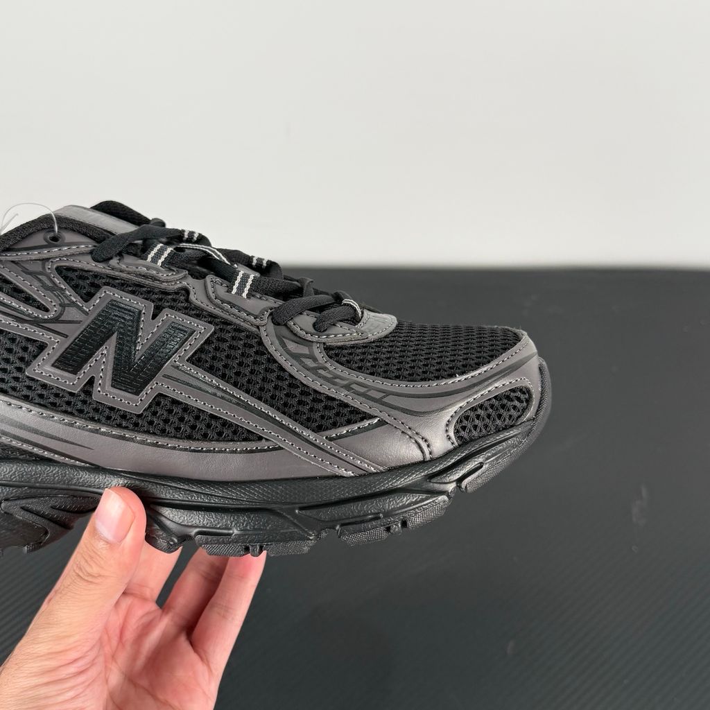 Side profile of the New Balance 740 sneaker in the 'Triple Black' colorway, showcasing the monochromatic mesh and synthetic upper, the tonal 'N' side logo, and the sculpted black midsole.