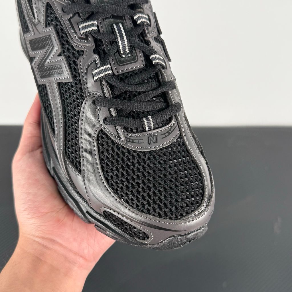 Side profile of the New Balance 740 sneaker in the 'Triple Black' colorway, showcasing the monochromatic mesh and synthetic upper, the tonal 'N' side logo, and the sculpted black midsole.