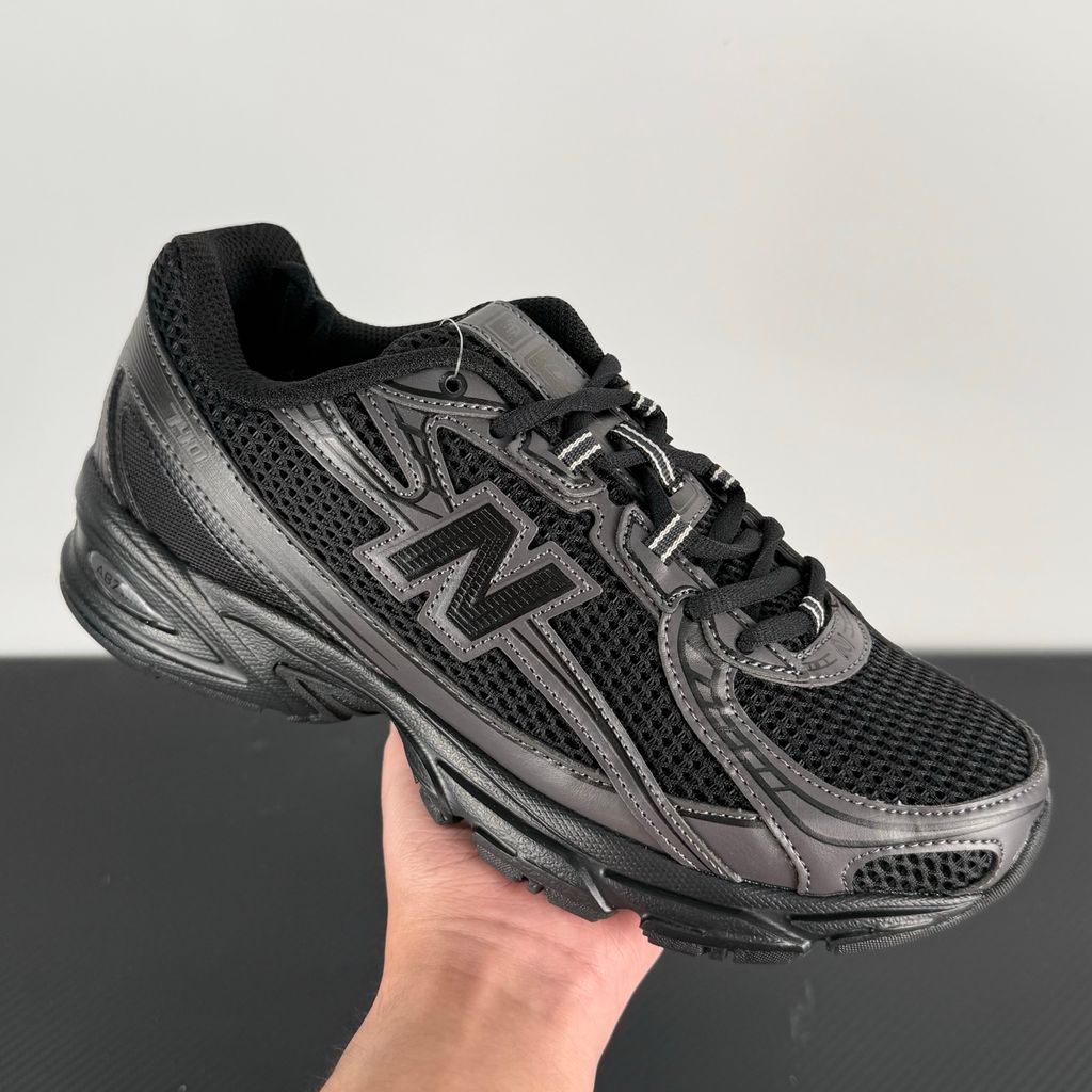 Side profile of the New Balance 740 sneaker in the 'Triple Black' colorway, showcasing the monochromatic mesh and synthetic upper, the tonal 'N' side logo, and the sculpted black midsole.
