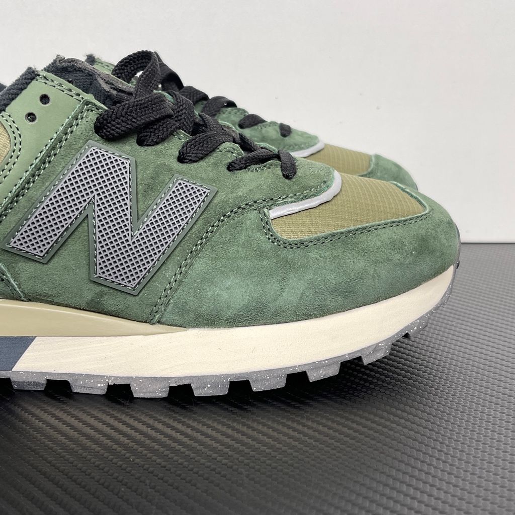 Side profile of the New Balance 574 Legacy Stone Island sneaker featuring a tactical dark green ripstop and suede upper, the iconic Stone Island compass logo on the tongue, and a rugged grey ENCAP midsole.