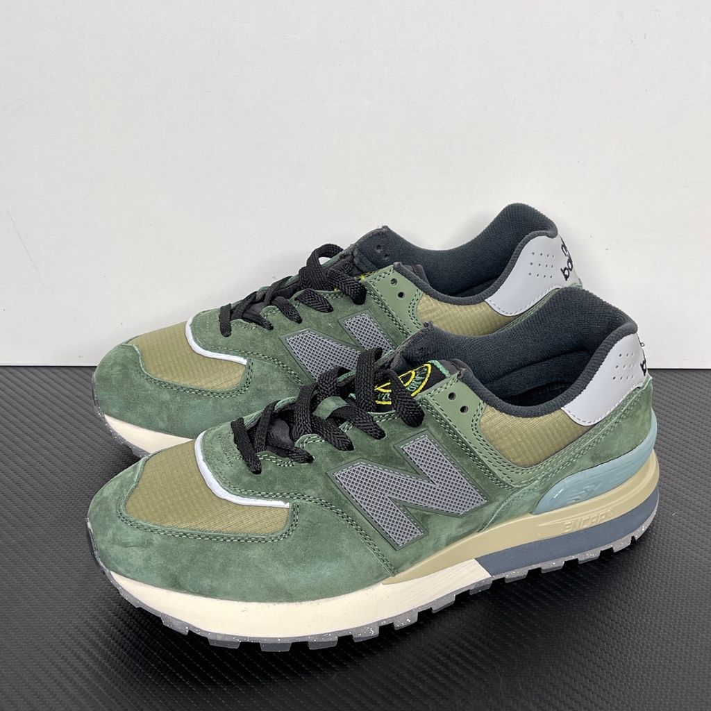 Side profile of the New Balance 574 Legacy Stone Island sneaker featuring a tactical dark green ripstop and suede upper, the iconic Stone Island compass logo on the tongue, and a rugged grey ENCAP midsole.