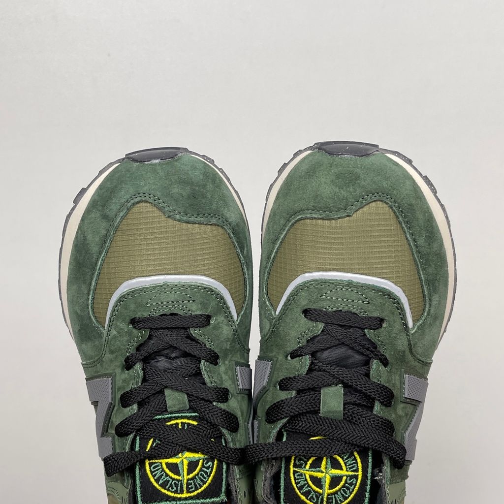 Side profile of the New Balance 574 Legacy Stone Island sneaker featuring a tactical dark green ripstop and suede upper, the iconic Stone Island compass logo on the tongue, and a rugged grey ENCAP midsole.