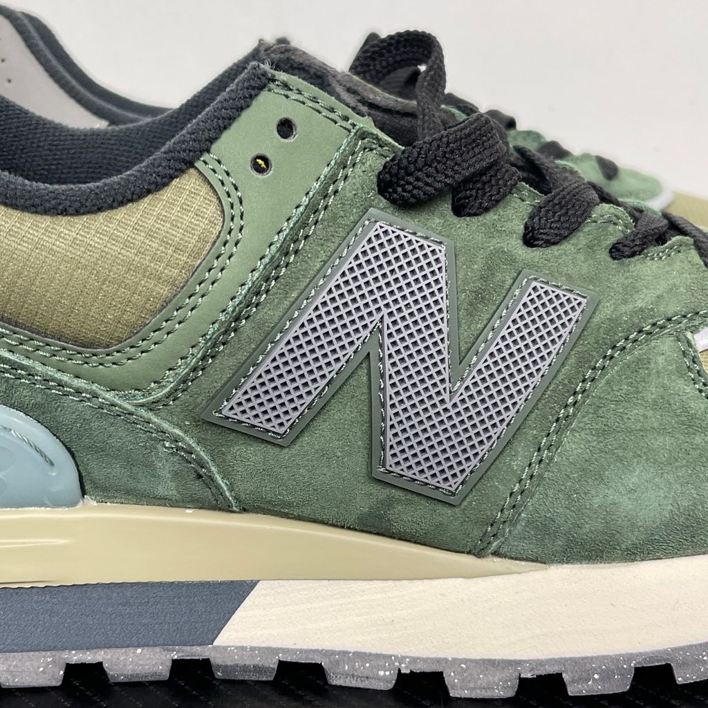 Side profile of the New Balance 574 Legacy Stone Island sneaker featuring a tactical dark green ripstop and suede upper, the iconic Stone Island compass logo on the tongue, and a rugged grey ENCAP midsole.