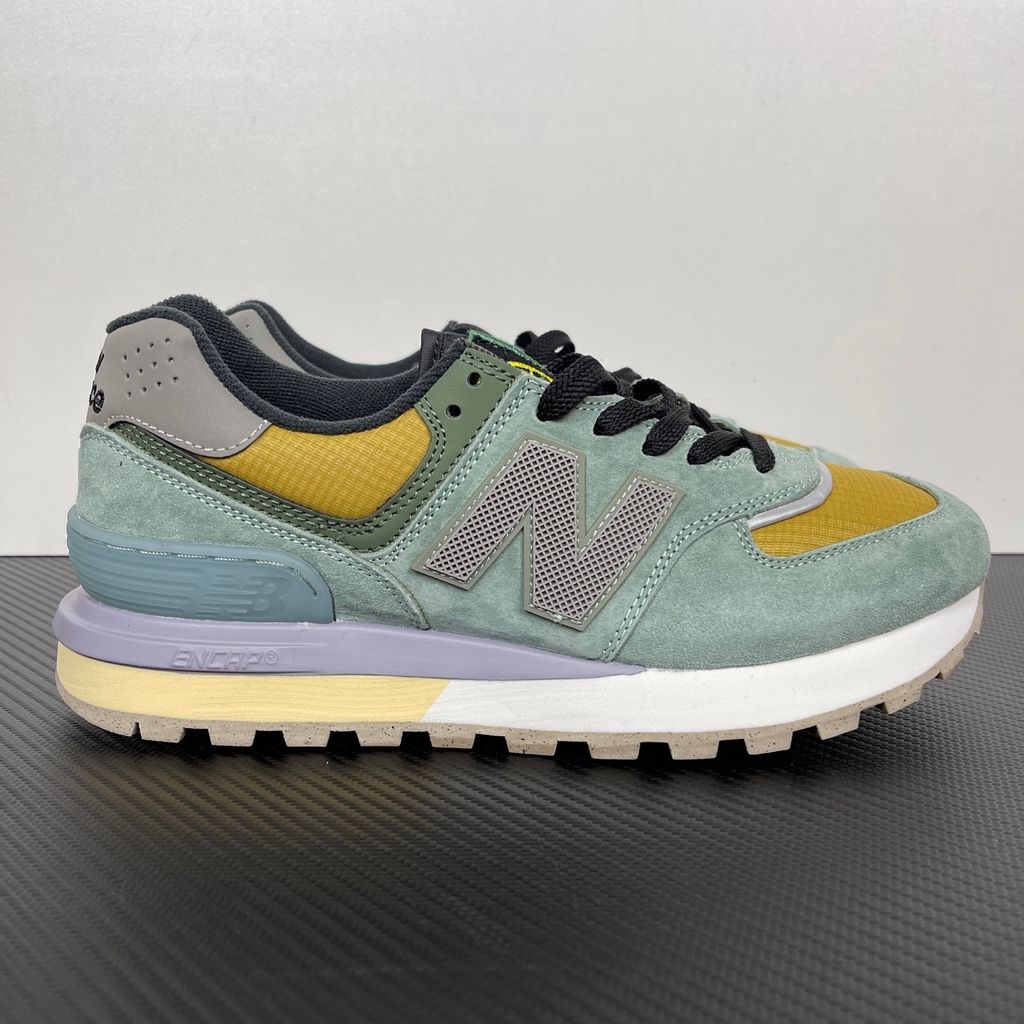 Side profile of the New Balance 574 Legacy Stone Island sneaker featuring a tactical light green ripstop and suede upper, the iconic Stone Island compass logo on the tongue, and a rugged grey ENCAP midsole.