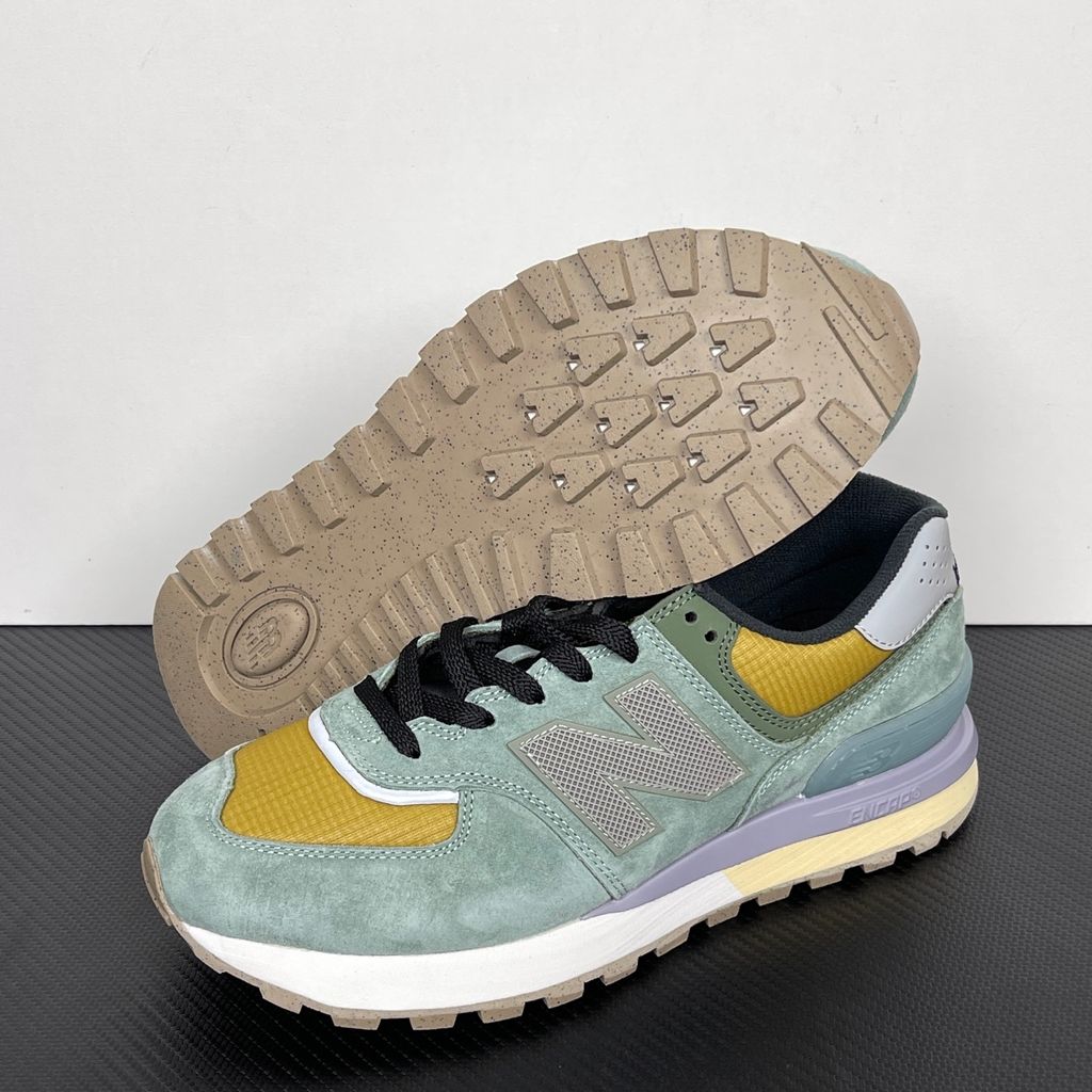 Side profile of the New Balance 574 Legacy Stone Island sneaker featuring a tactical light green ripstop and suede upper, the iconic Stone Island compass logo on the tongue, and a rugged grey ENCAP midsole.