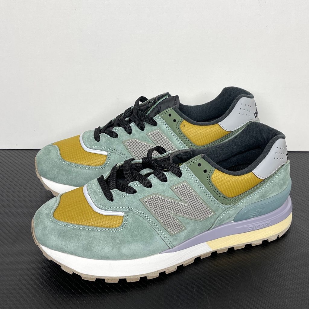 Side profile of the New Balance 574 Legacy Stone Island sneaker featuring a tactical light green ripstop and suede upper, the iconic Stone Island compass logo on the tongue, and a rugged grey ENCAP midsole.