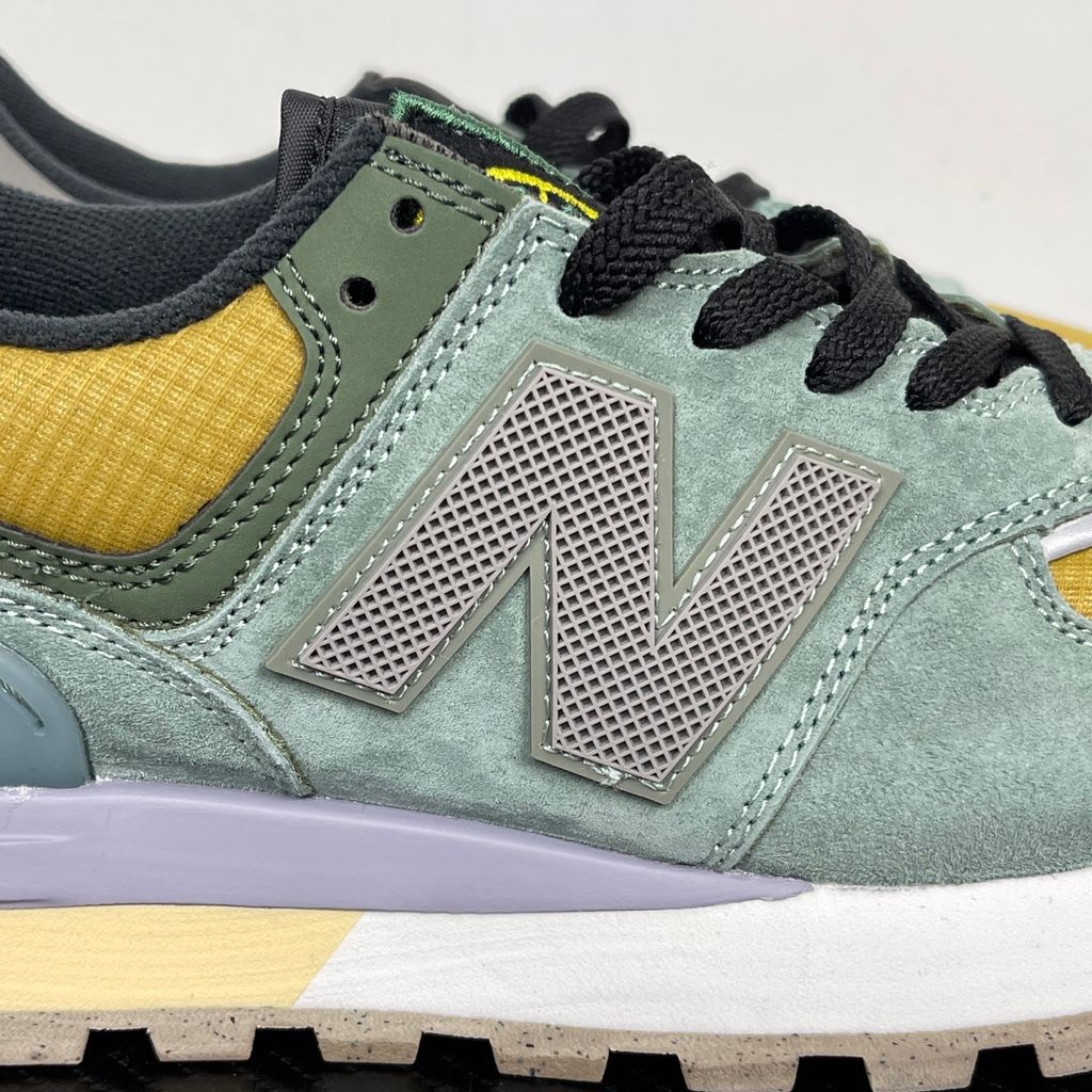 Side profile of the New Balance 574 Legacy Stone Island sneaker featuring a tactical light green ripstop and suede upper, the iconic Stone Island compass logo on the tongue, and a rugged grey ENCAP midsole.