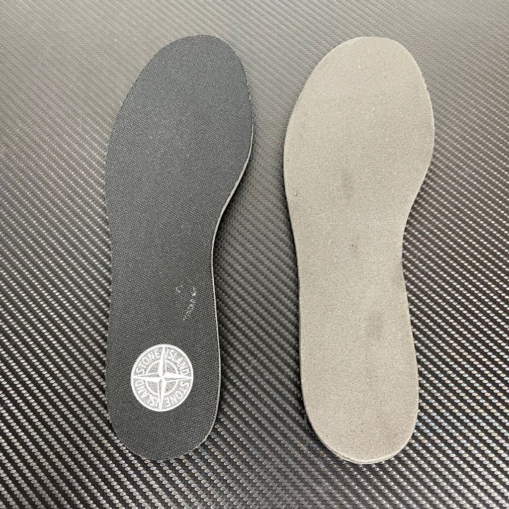 Side profile of the New Balance 574 Legacy Stone Island sneaker featuring a tactical light green ripstop and suede upper, the iconic Stone Island compass logo on the tongue, and a rugged grey ENCAP midsole.