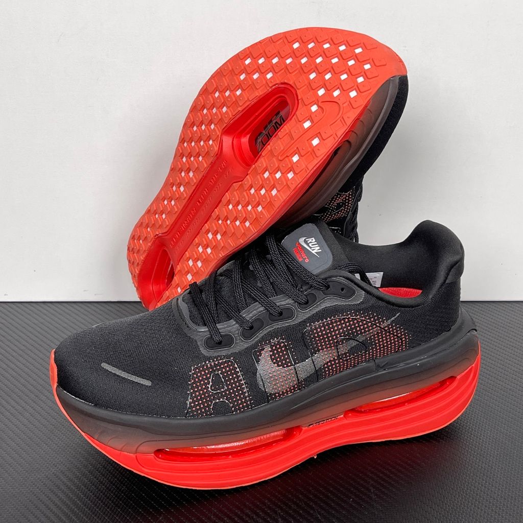 Side profile of the Nike Vomero Premium sneaker featuring a stealthy black mesh upper with oversized 'AIR' branding, and a massive gradient platform midsole transitioning from black to bright crimson with exposed Zoom Air units.