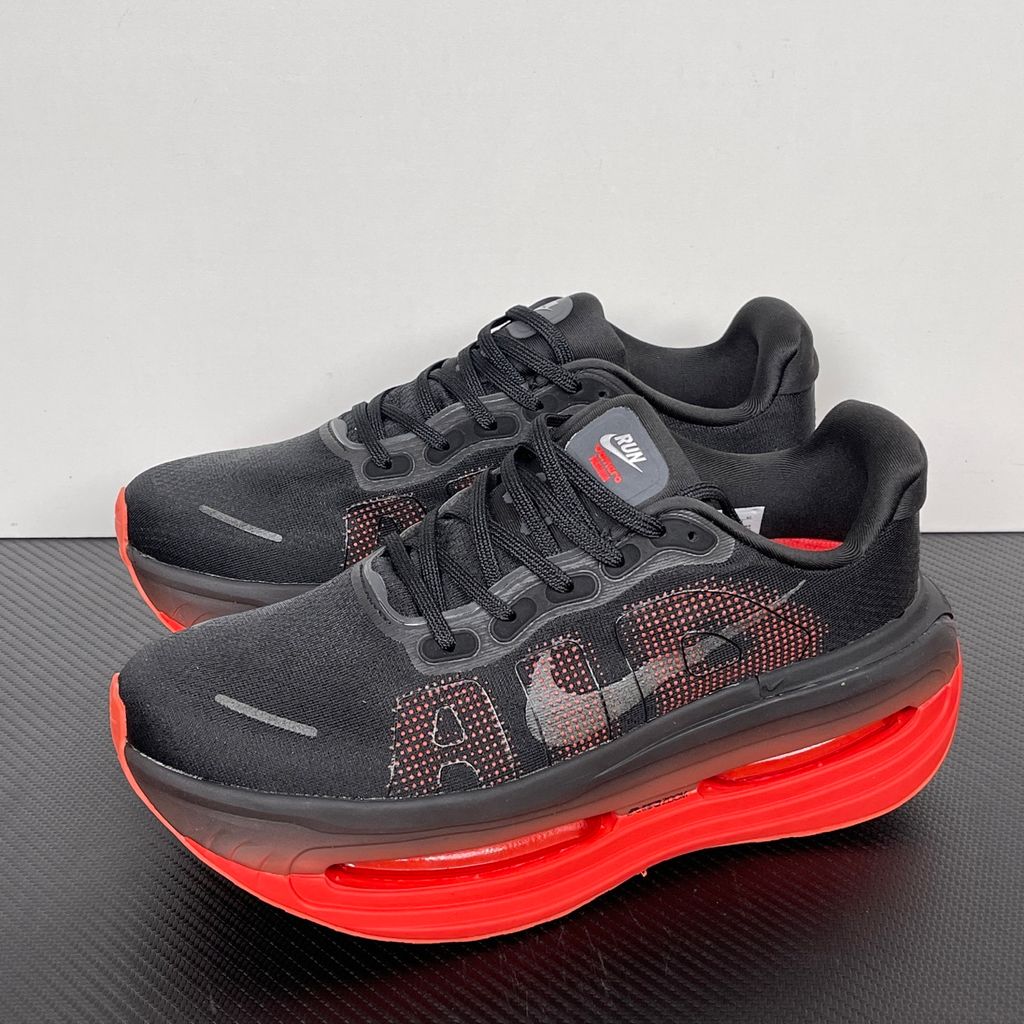 Side profile of the Nike Vomero Premium sneaker featuring a stealthy black mesh upper with oversized 'AIR' branding, and a massive gradient platform midsole transitioning from black to bright crimson with exposed Zoom Air units.