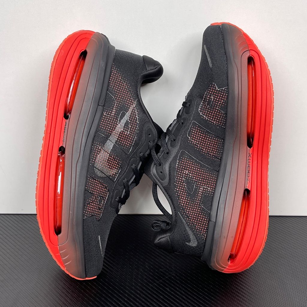 Side profile of the Nike Vomero Premium sneaker featuring a stealthy black mesh upper with oversized 'AIR' branding, and a massive gradient platform midsole transitioning from black to bright crimson with exposed Zoom Air units.