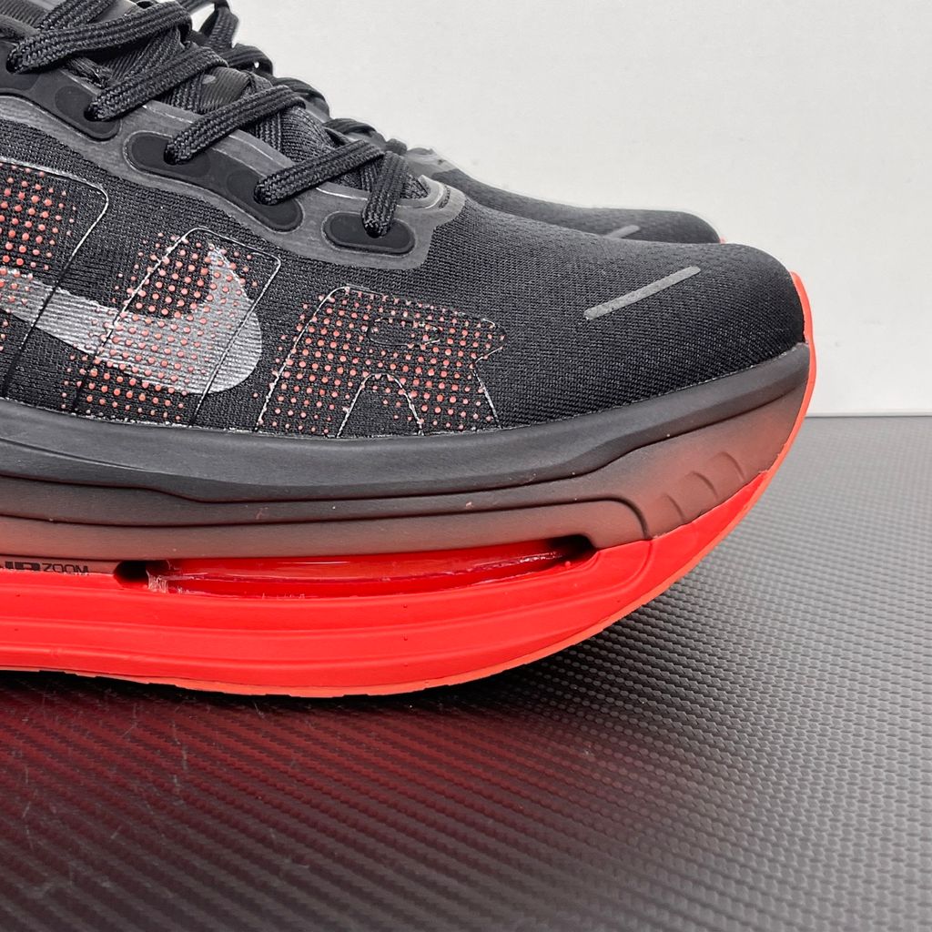 Side profile of the Nike Vomero Premium sneaker featuring a stealthy black mesh upper with oversized 'AIR' branding, and a massive gradient platform midsole transitioning from black to bright crimson with exposed Zoom Air units.