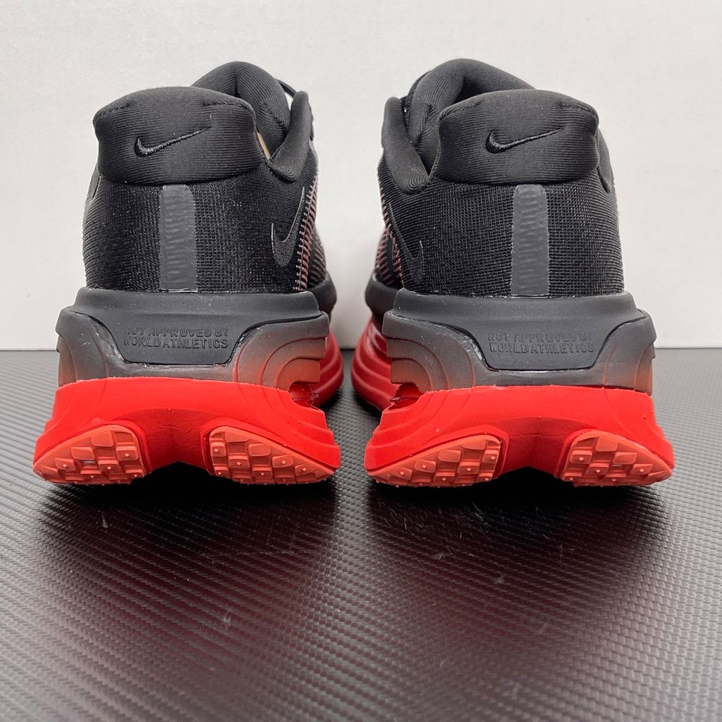 Side profile of the Nike Vomero Premium sneaker featuring a stealthy black mesh upper with oversized 'AIR' branding, and a massive gradient platform midsole transitioning from black to bright crimson with exposed Zoom Air units.