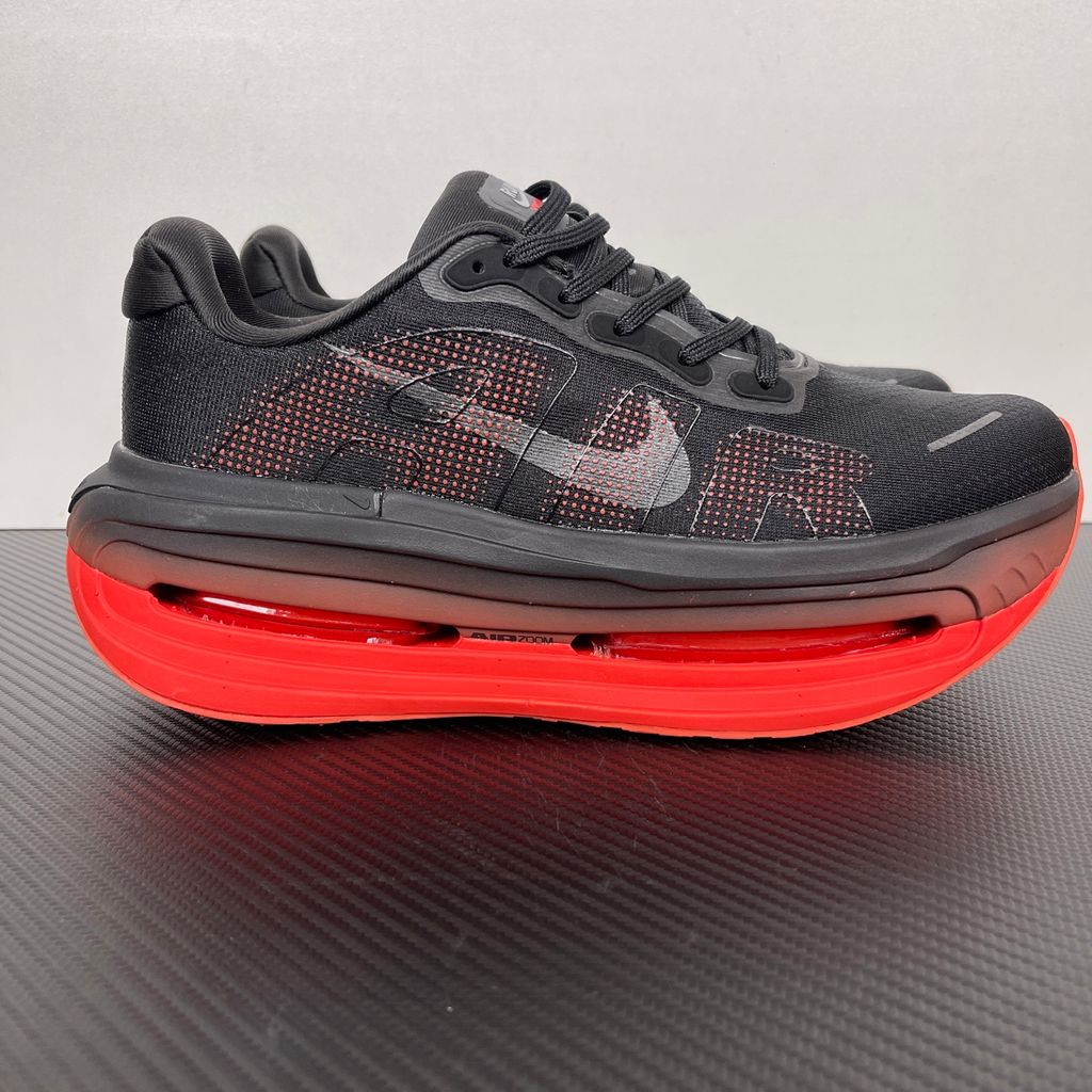 Side profile of the Nike Vomero Premium sneaker featuring a stealthy black mesh upper with oversized 'AIR' branding, and a massive gradient platform midsole transitioning from black to bright crimson with exposed Zoom Air units.