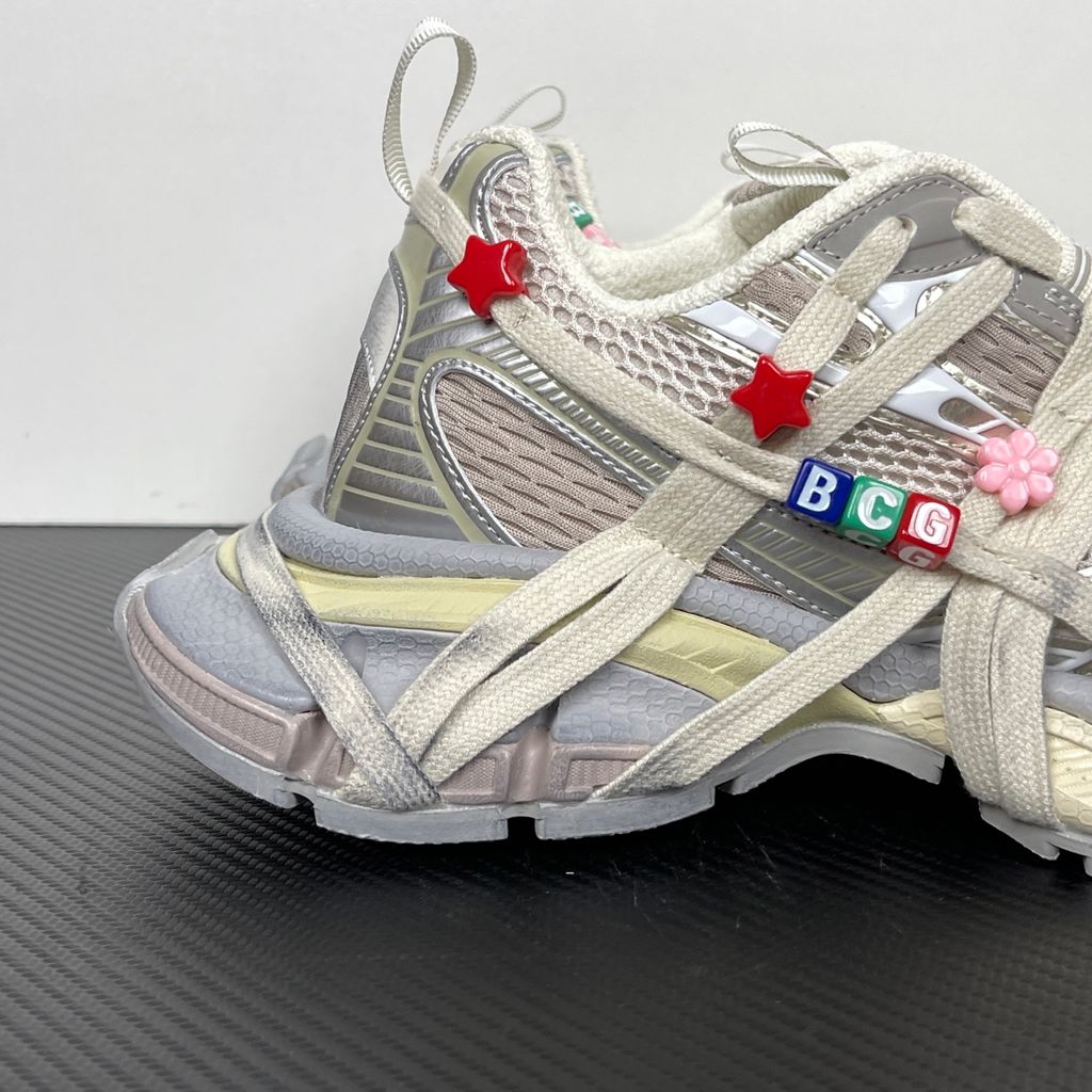 Side profile of the Balenciaga 3XL Extreme Lace sneaker in an eggshell and multicolor palette, highlighting the heavily distressed chunky rubber sole, worn-in mesh upper, and the signature extreme wraparound laces covering the toe box and midsole.