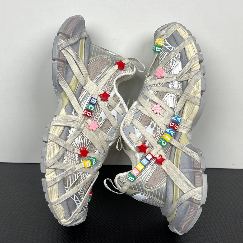 Side profile of the Balenciaga 3XL Extreme Lace sneaker in an eggshell and multicolor palette, highlighting the heavily distressed chunky rubber sole, worn-in mesh upper, and the signature extreme wraparound laces covering the toe box and midsole.