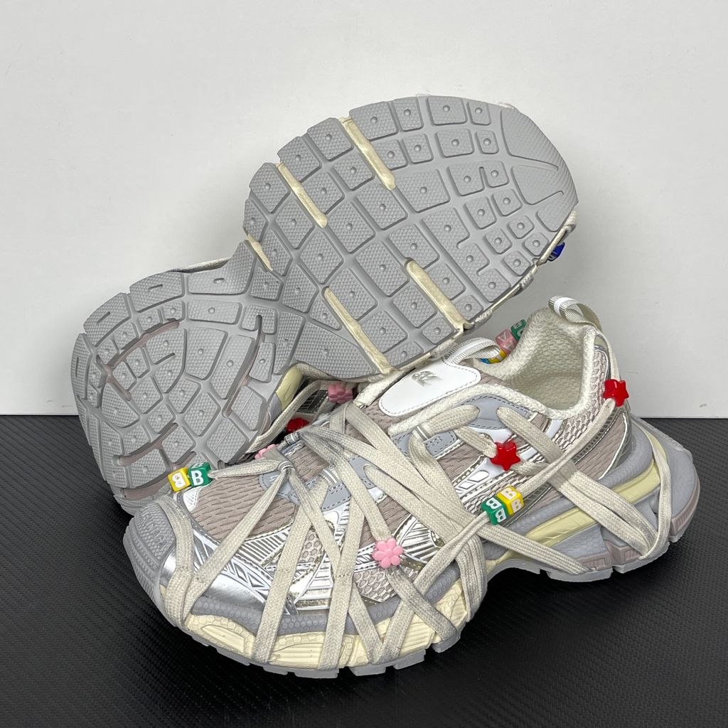 Side profile of the Balenciaga 3XL Extreme Lace sneaker in an eggshell and multicolor palette, highlighting the heavily distressed chunky rubber sole, worn-in mesh upper, and the signature extreme wraparound laces covering the toe box and midsole.