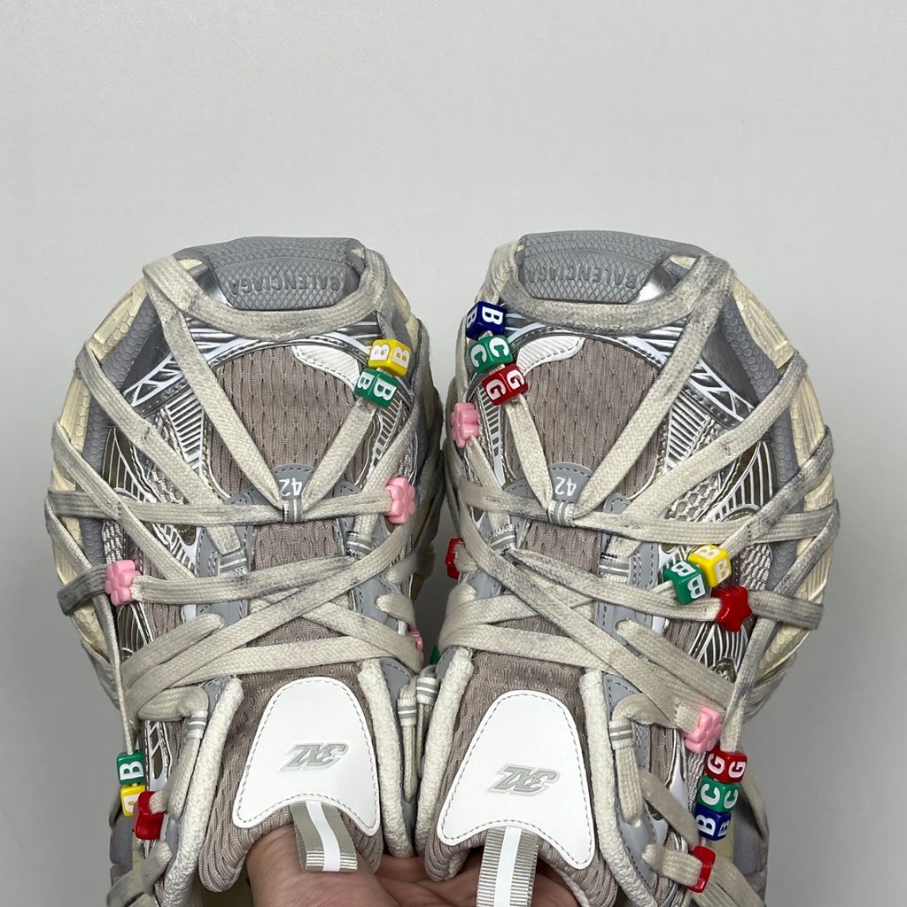 Side profile of the Balenciaga 3XL Extreme Lace sneaker in an eggshell and multicolor palette, highlighting the heavily distressed chunky rubber sole, worn-in mesh upper, and the signature extreme wraparound laces covering the toe box and midsole.