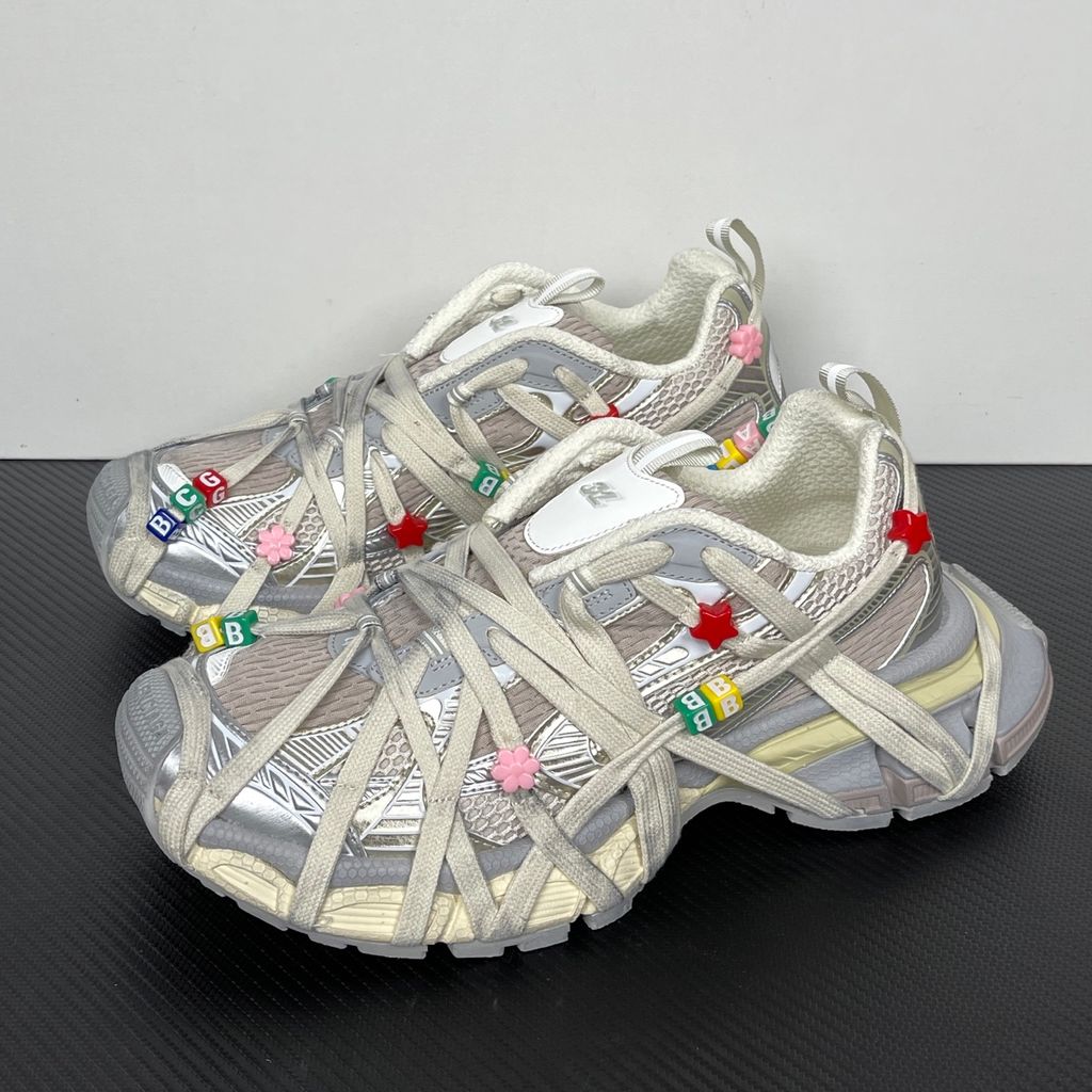 Side profile of the Balenciaga 3XL Extreme Lace sneaker in an eggshell and multicolor palette, highlighting the heavily distressed chunky rubber sole, worn-in mesh upper, and the signature extreme wraparound laces covering the toe box and midsole.
