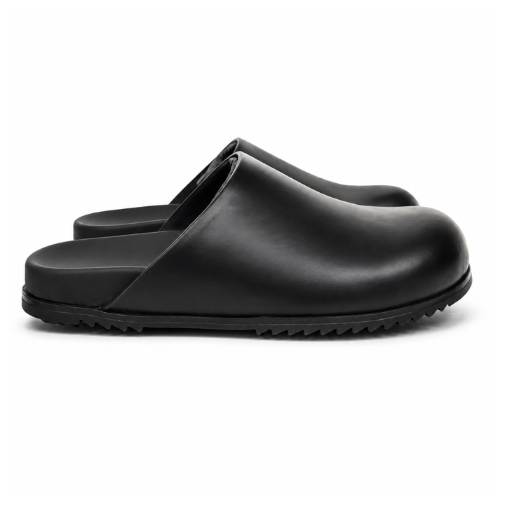 Side profile of the Rick Owens Mule Granola in smooth black leather, featuring a minimalist slip-on silhouette, an exaggerated rounded toe box, and a signature dark jagged rubber outsole.